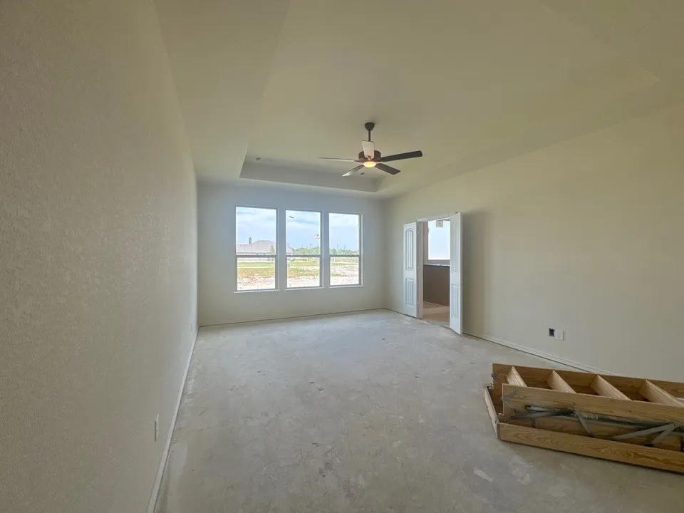 Tray ceiling with ceiling fan, large windows, and double French doors