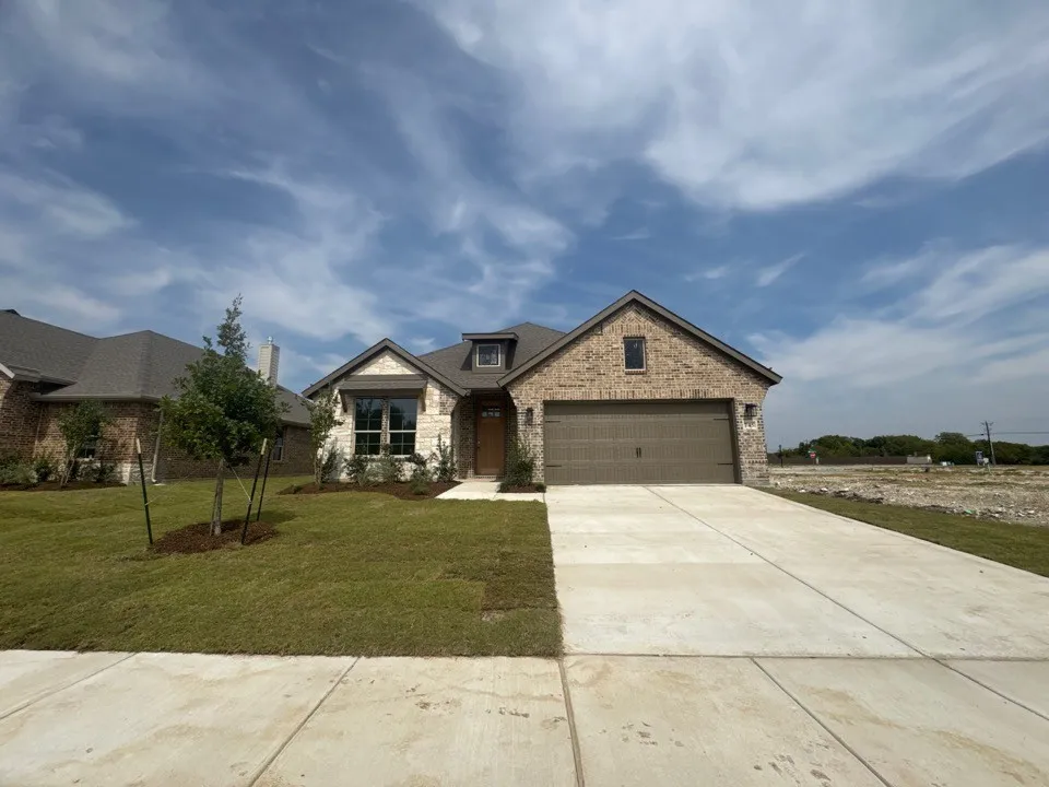 Brick and stone exterior with a gabled roofline, front-facing garage, and a concrete driveway