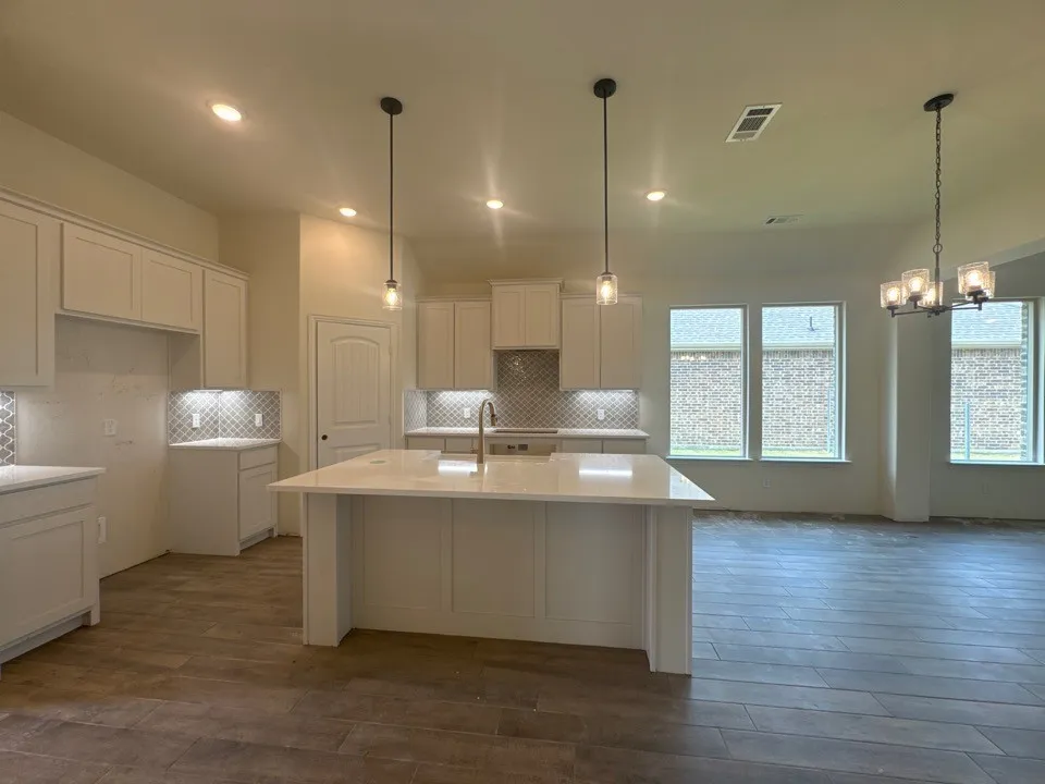 Kitchen with light-toned cabinetry, a large center island with a light-toned countertop, and tile flooring