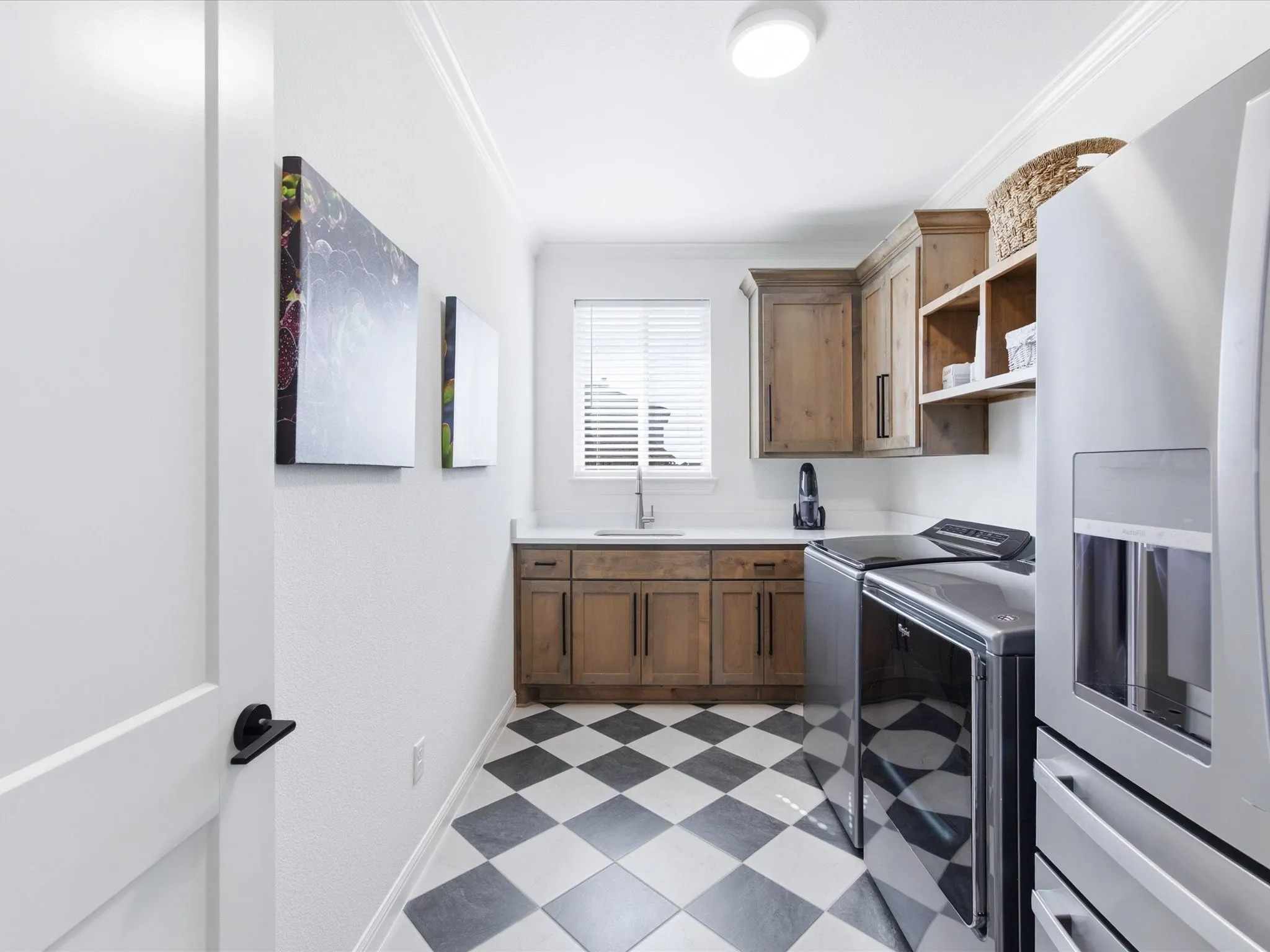 The spacious laundry room has built-in cabinets, sink, and room for a refrigerator.