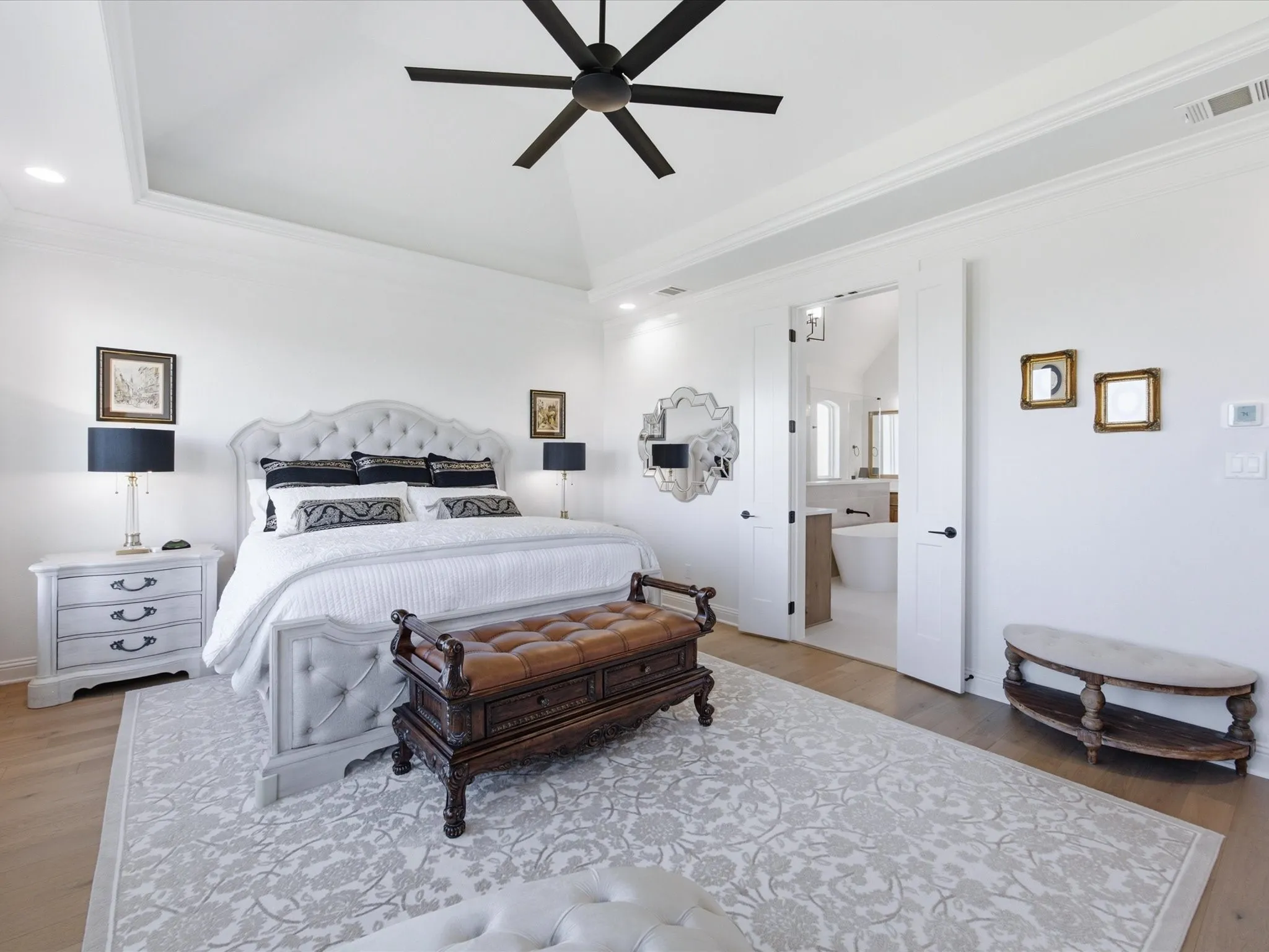 Elegant primary bedroom featuring a tray ceiling, beautiful hardwood floors, and a serene neutral palette with direct access to the luxurious ensuite bath.