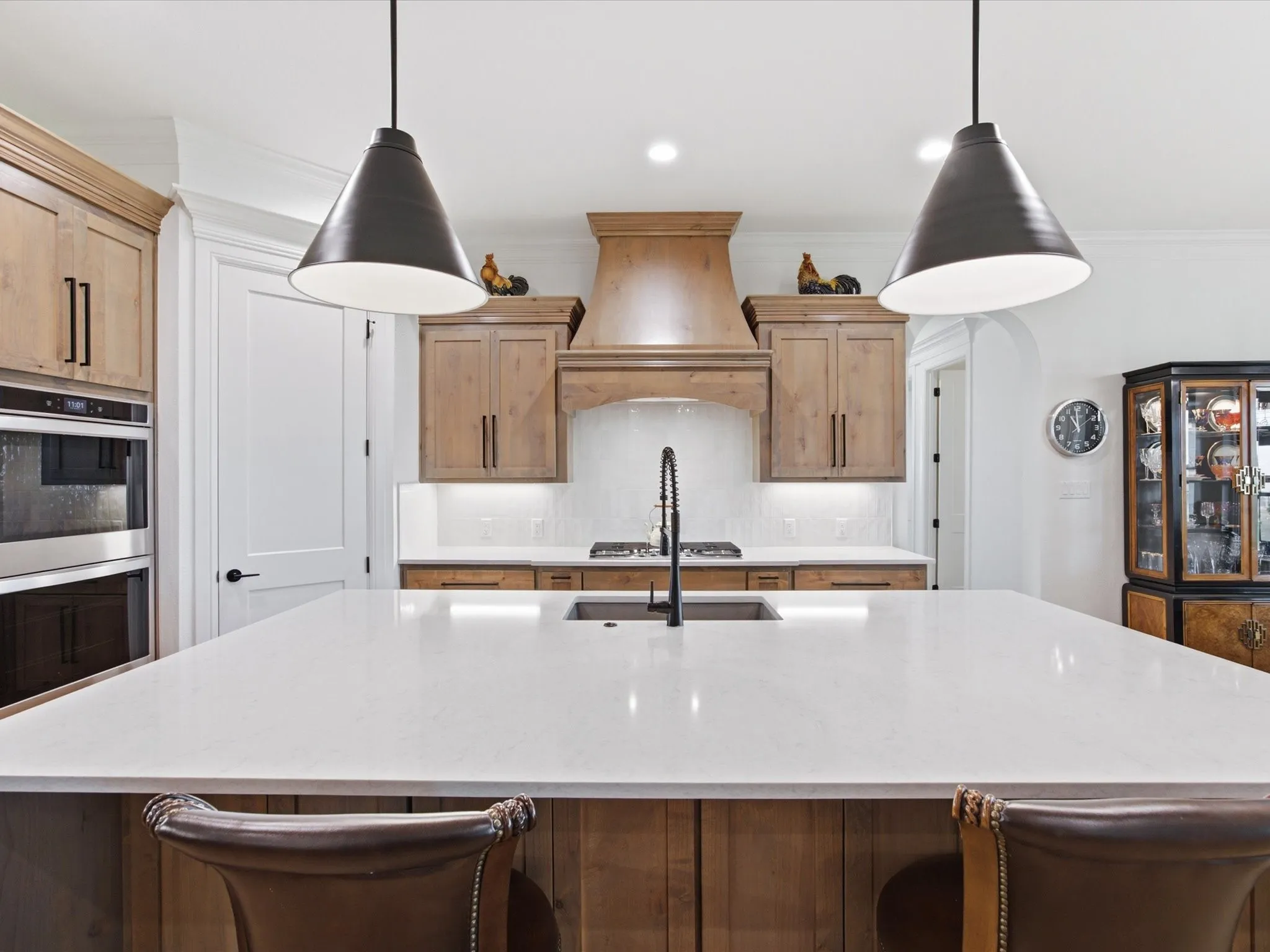 Stunning pendant lights illuminate the large island with quartz counter-tops.