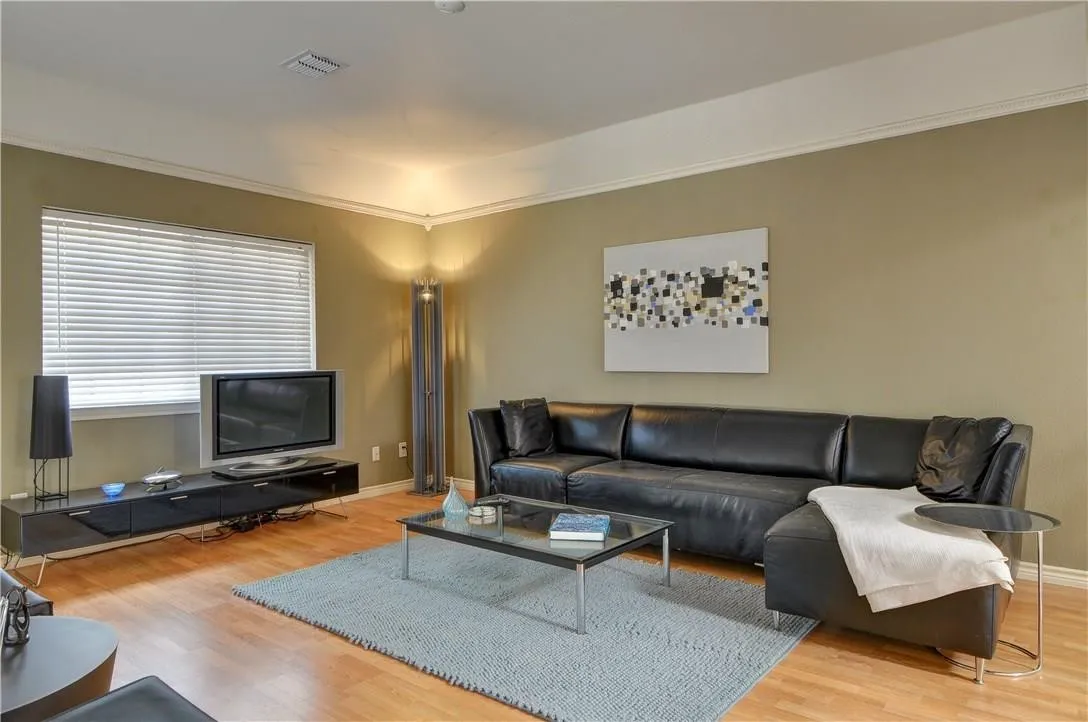 Wood-finish flooring with crown molding and recessed lighting