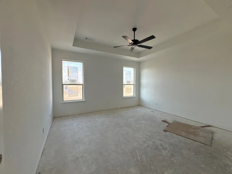 Tray ceiling with a black ceiling fan, two double-hung windows, and painted white walls