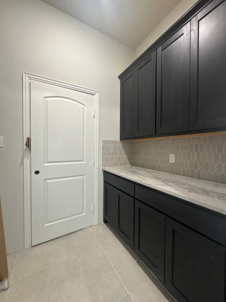 Built-in cabinetry with a light-toned countertop, honeycomb tile backsplash, and light-toned floor tile