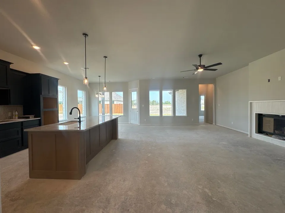 Spacious open-concept layout featuring a large kitchen island, dark cabinetry, a built-in fireplace, and multiple windows