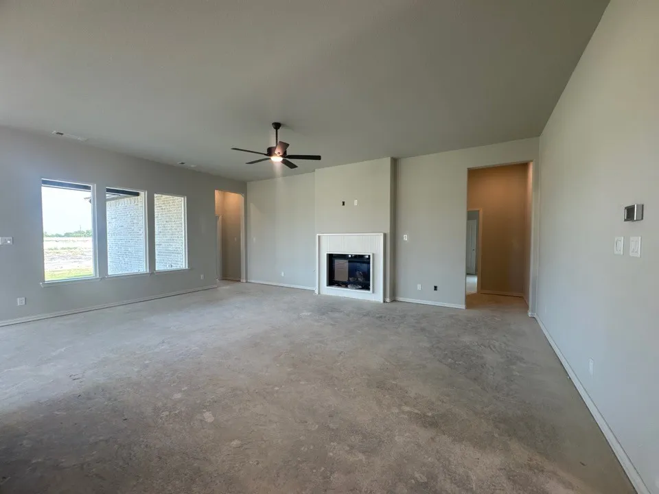 Spacious living area featuring a contemporary fireplace, multiple windows, a ceiling fan, and recessed lighting