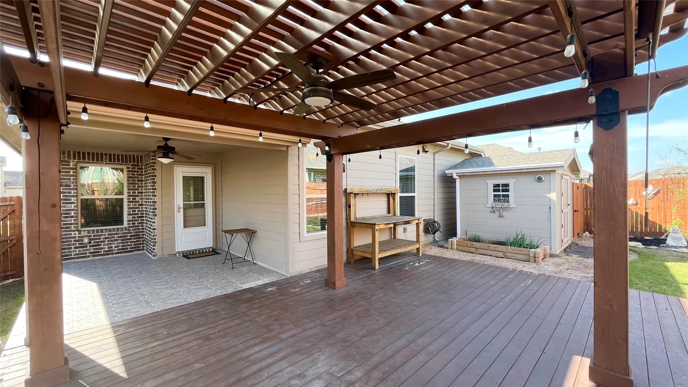 Expansive outdoor living area featuring a wood pergola, composite decking, and string lighting