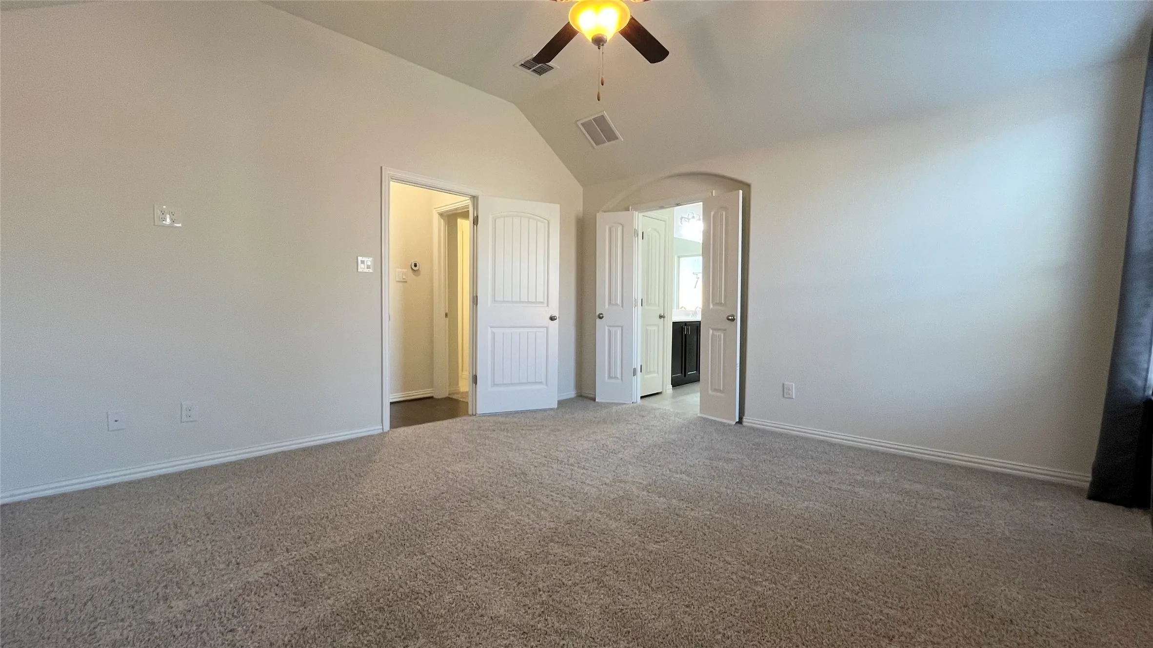 Vaulted ceiling with a ceiling fan, carpet flooring, arched doorway, and white paneled doors