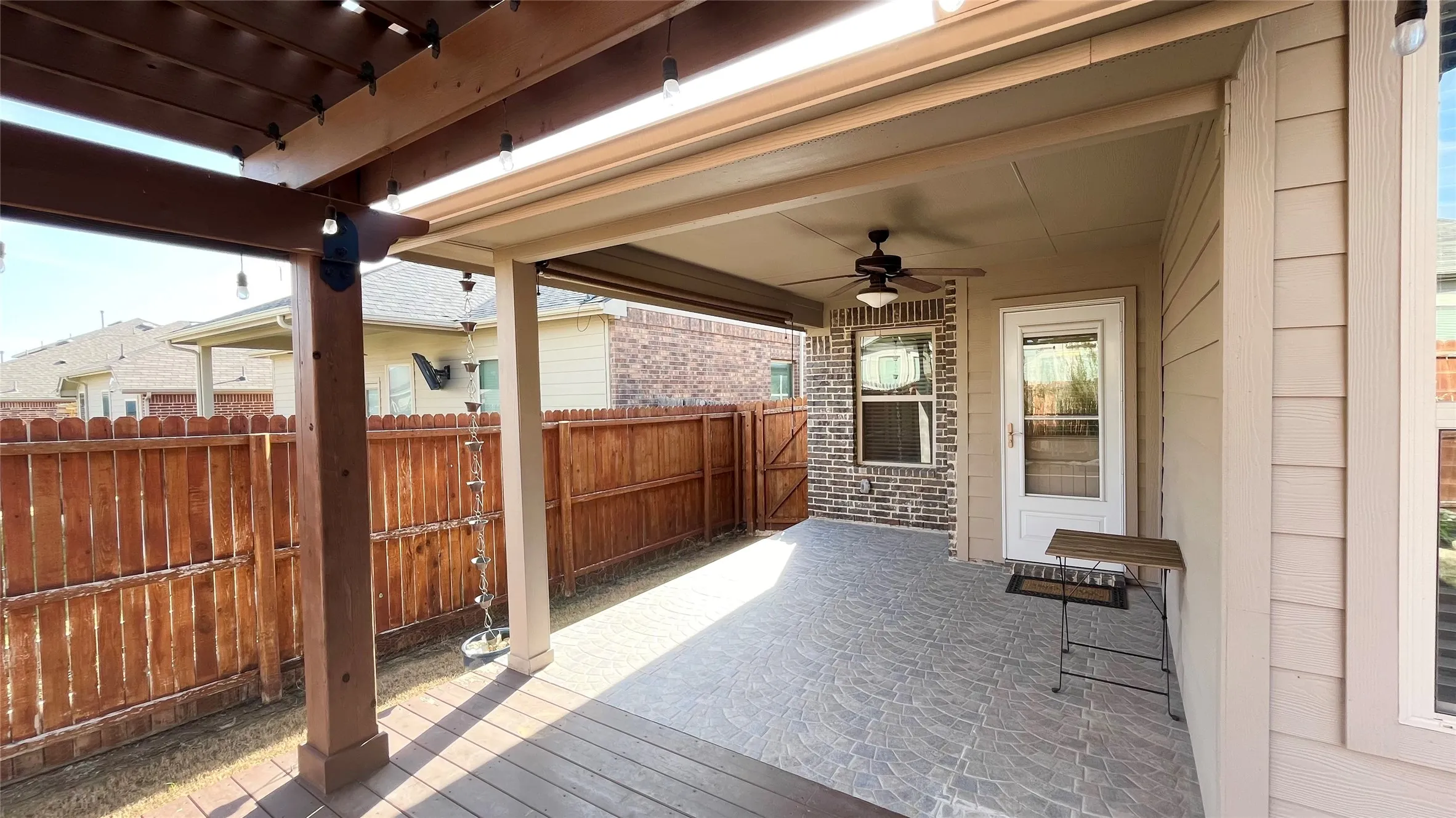 Covered patio featuring a ceiling fan, patterned concrete flooring, and a wood pergola