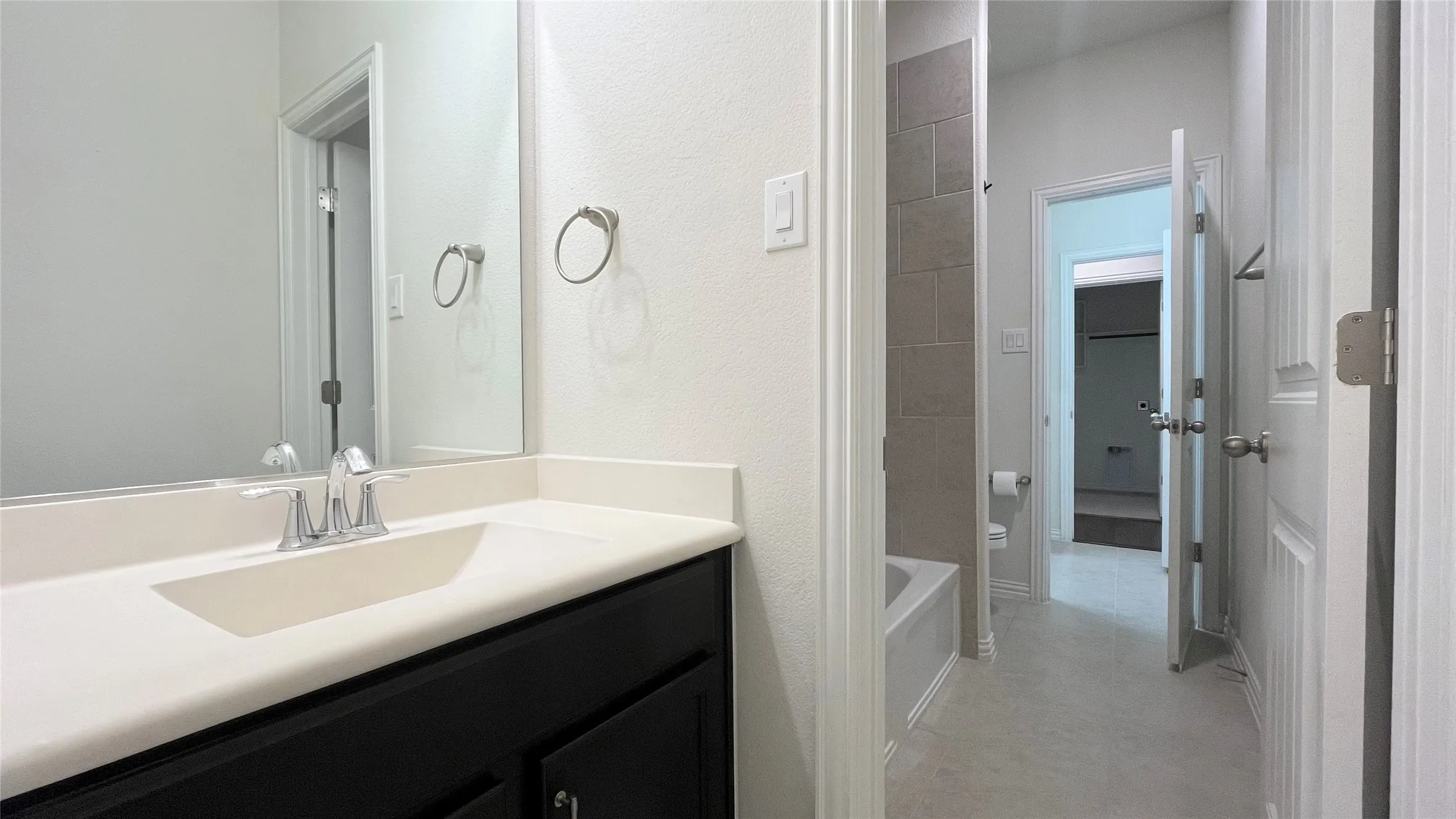 Bathroom featuring a single vanity with integrated sink, chrome faucet, and a large mirror