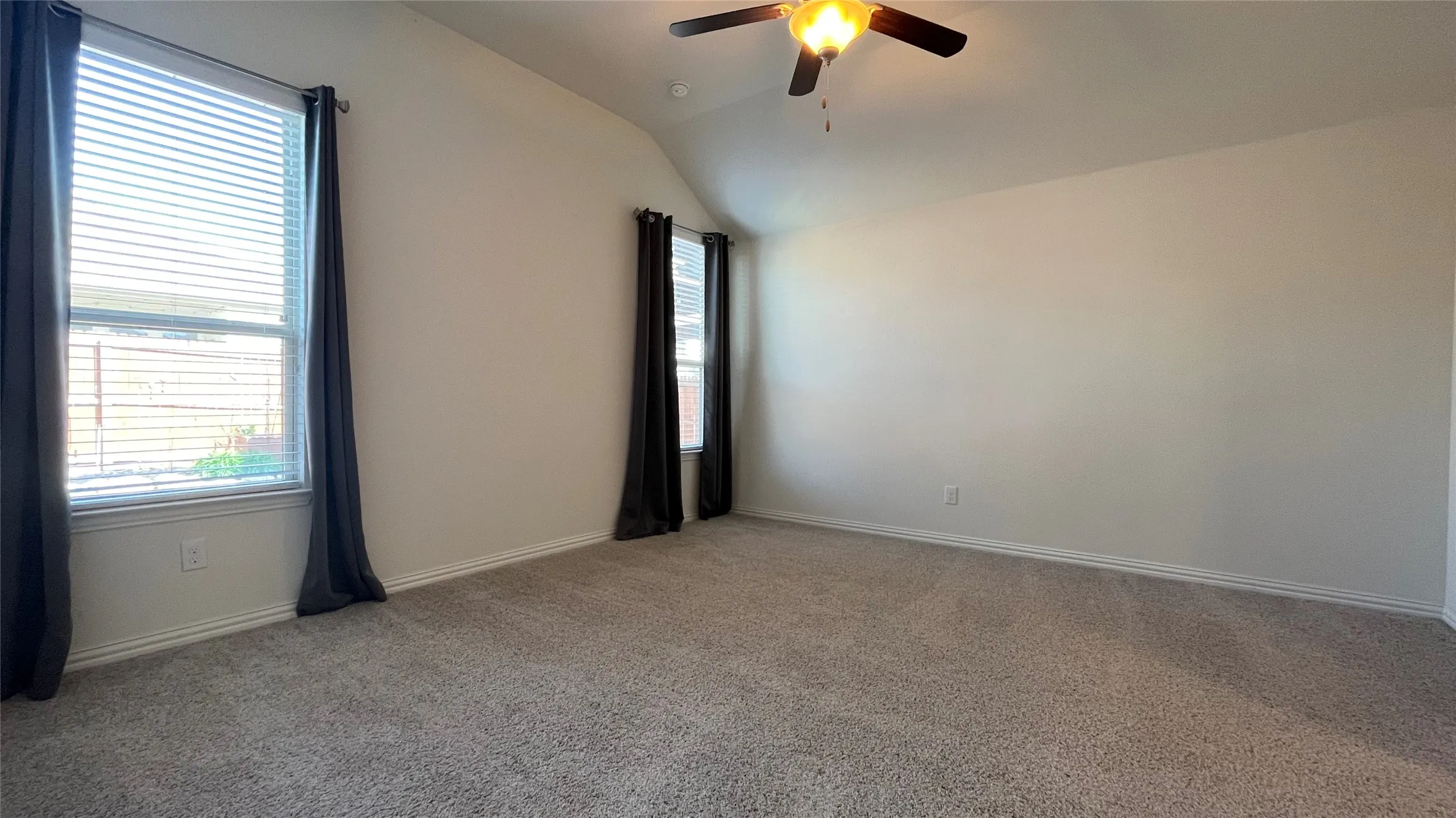 Plush carpet flooring, vaulted ceiling, and dual windows