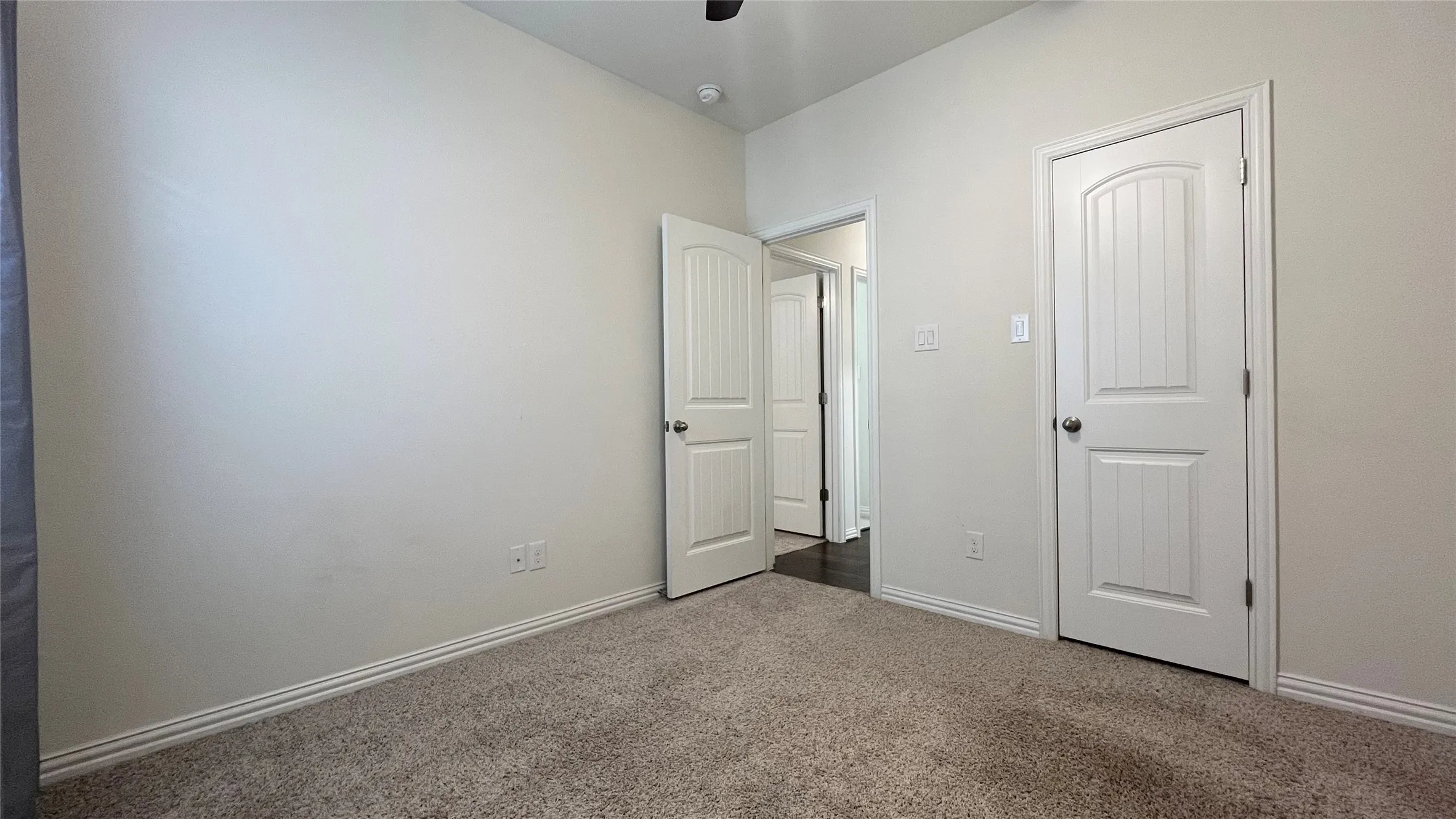 Carpeted flooring, neutral wall color, white paneled doors, ceiling fan