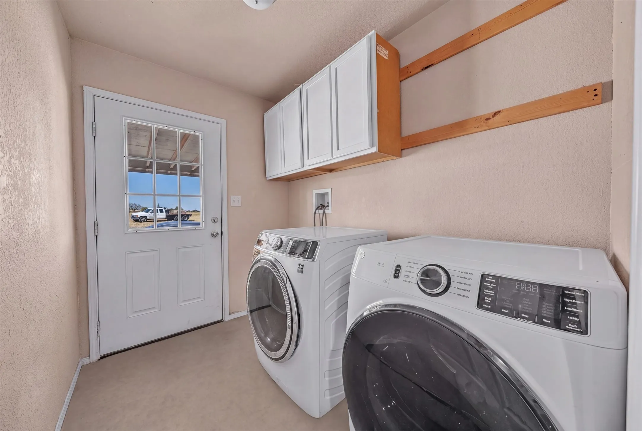 Dedicated laundry area with upper cabinetry and a windowed exterior door
