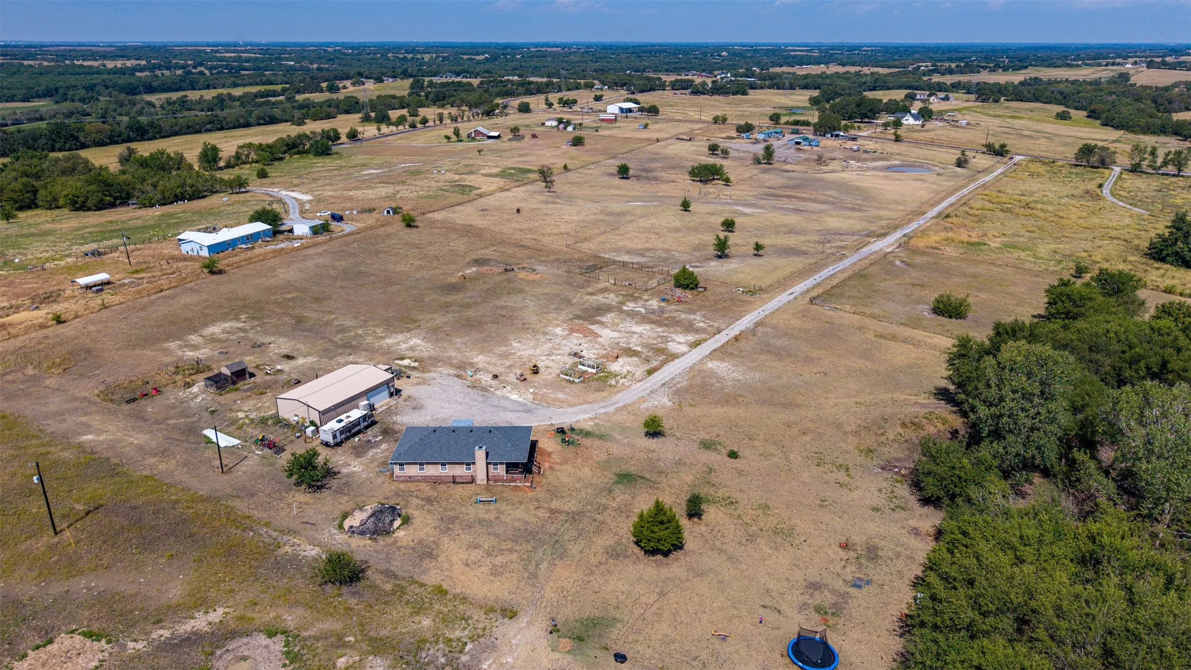 Rural landscape featuring multiple structures, extensive open terrain, and dense tree lines