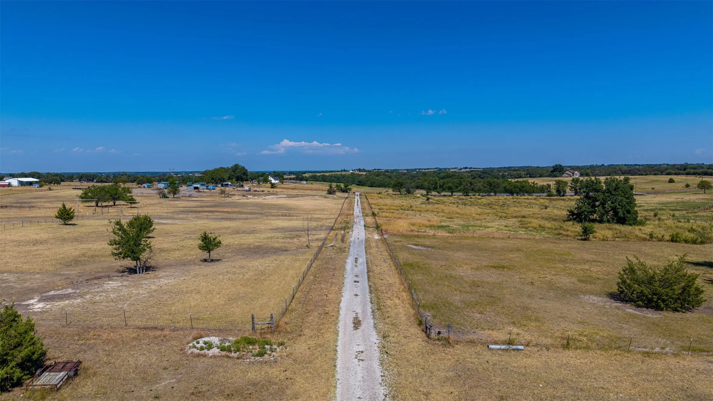 Expansive acreage featuring a long private drive, perimeter fencing, and scattered mature trees