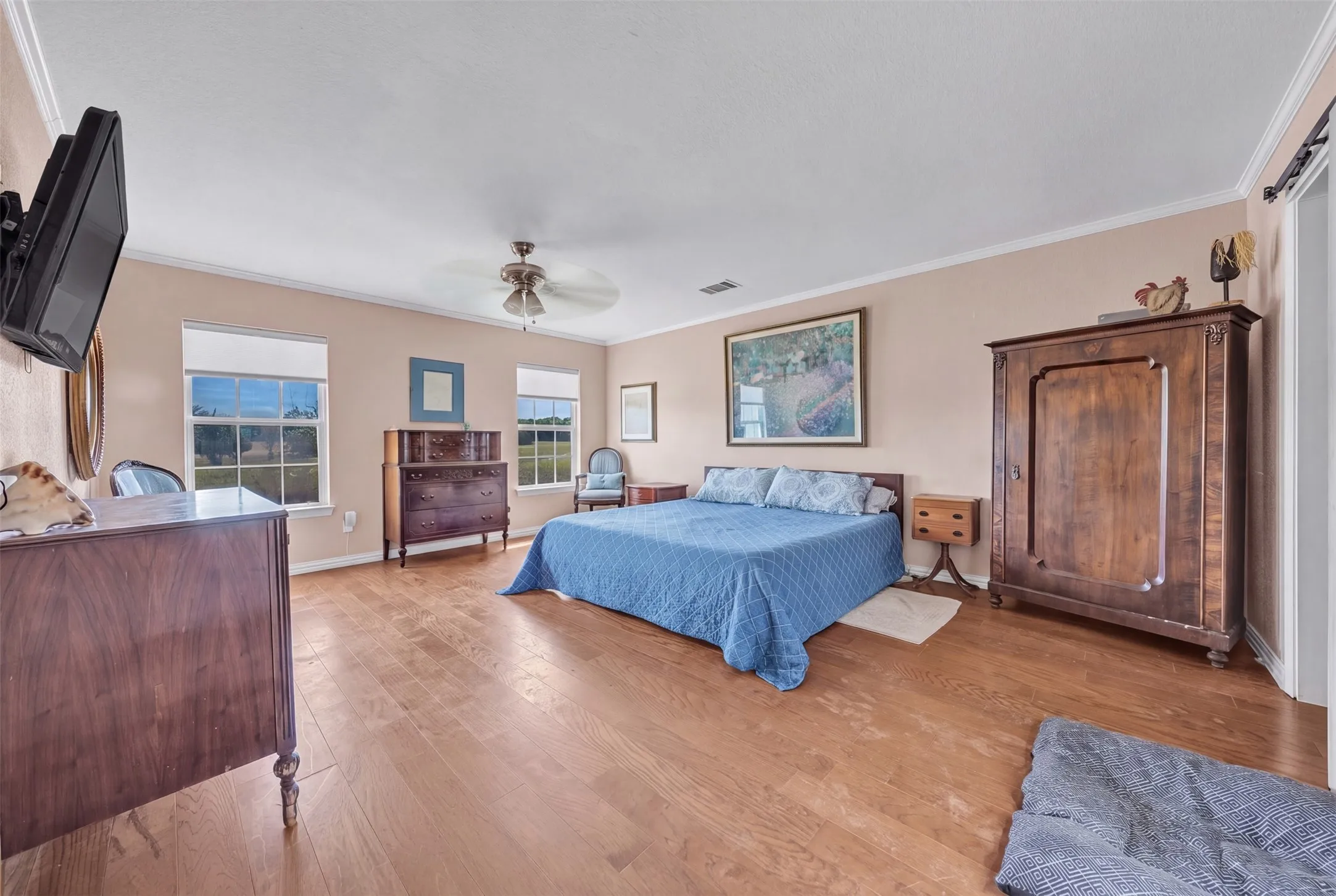 Wood-finish flooring throughout, crown molding, and a ceiling fan