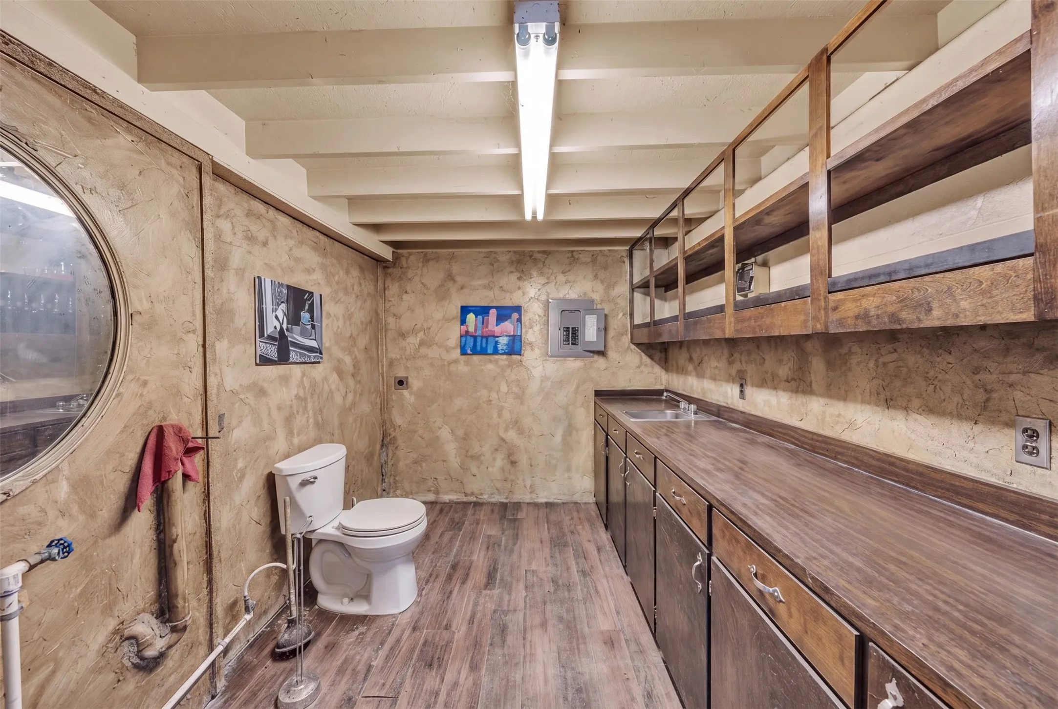 Wood-finish flooring, exposed ceiling beams, built-in shelving, wood-finish countertops, and a utility sink