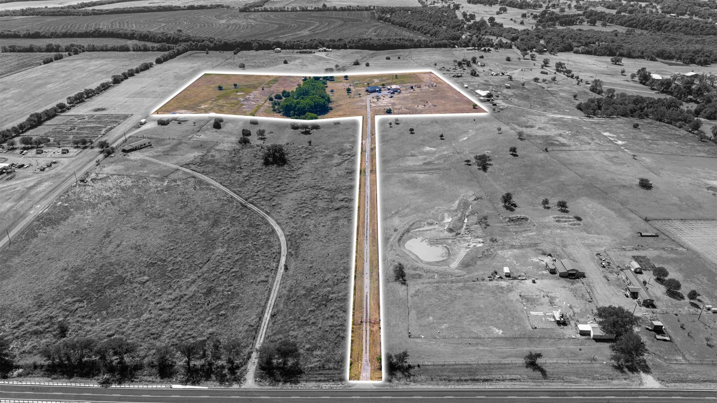 Expansive land parcel with a private drive, natural tree coverage, and a water feature