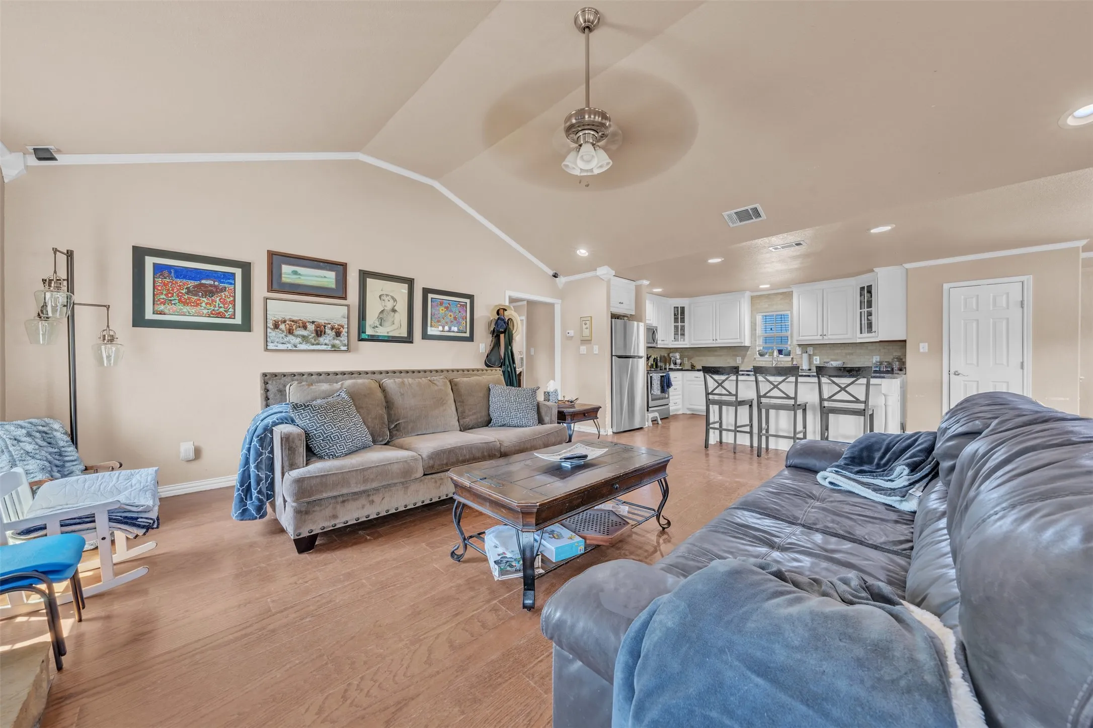 Open-concept living area featuring wood-finish flooring, a vaulted ceiling, and recessed lighting