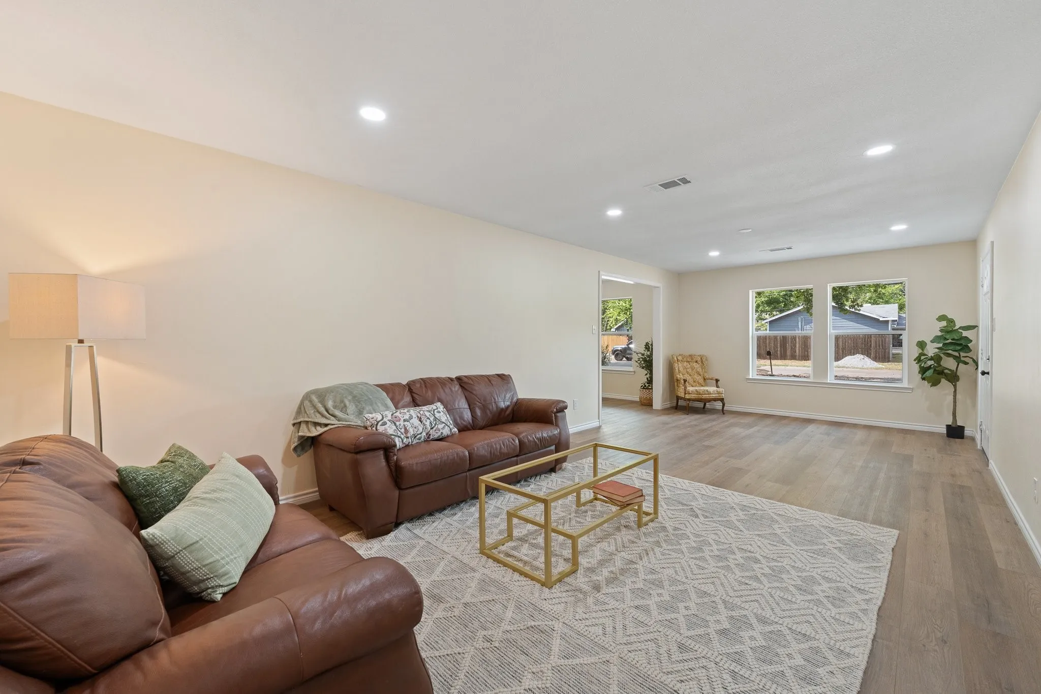 Spacious living area featuring recessed lighting, wood-finish flooring, and multiple windows for natural light