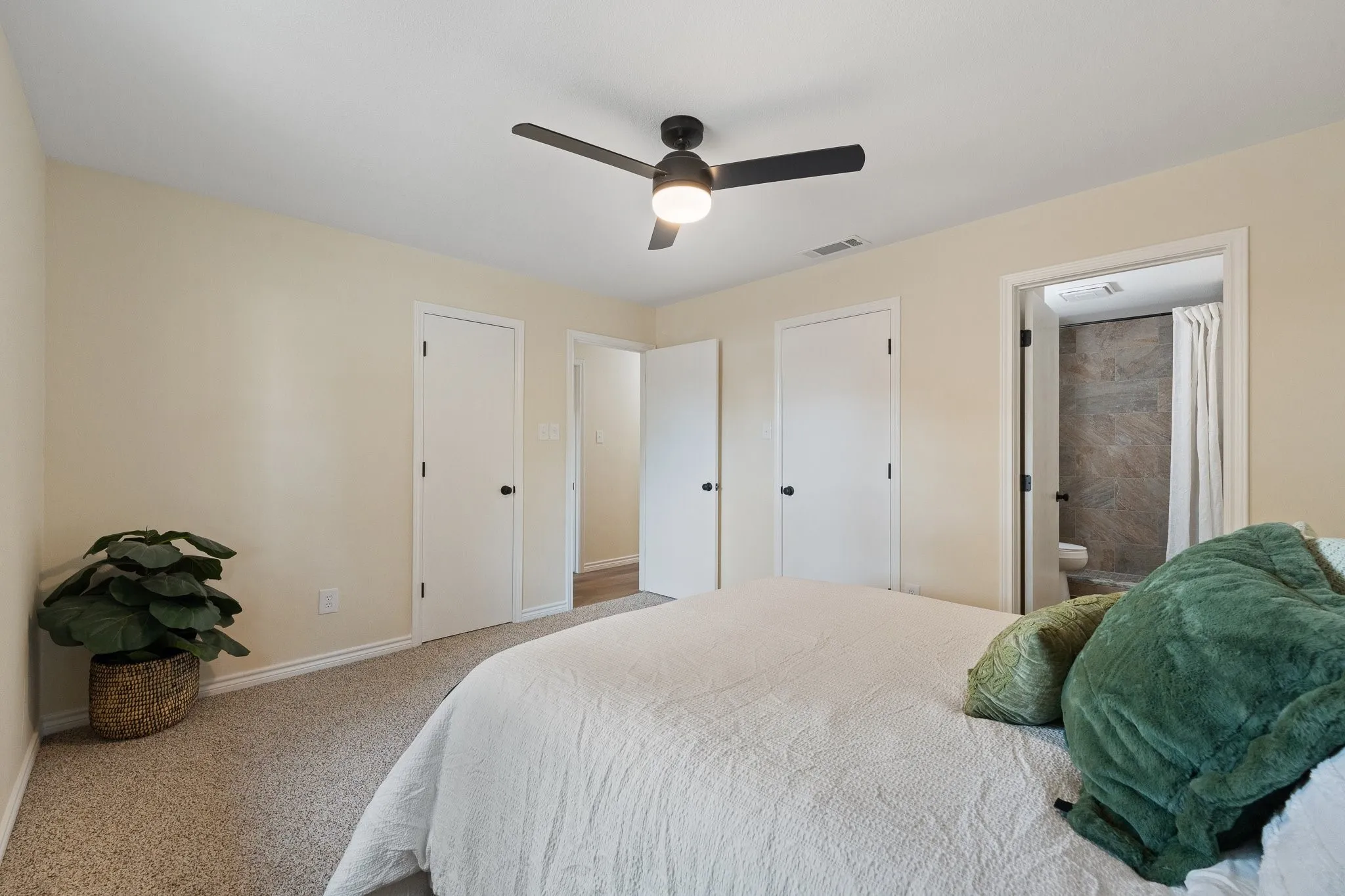 Ceiling fan with integrated lighting, neutral carpet flooring, and interior doors with dark hardware