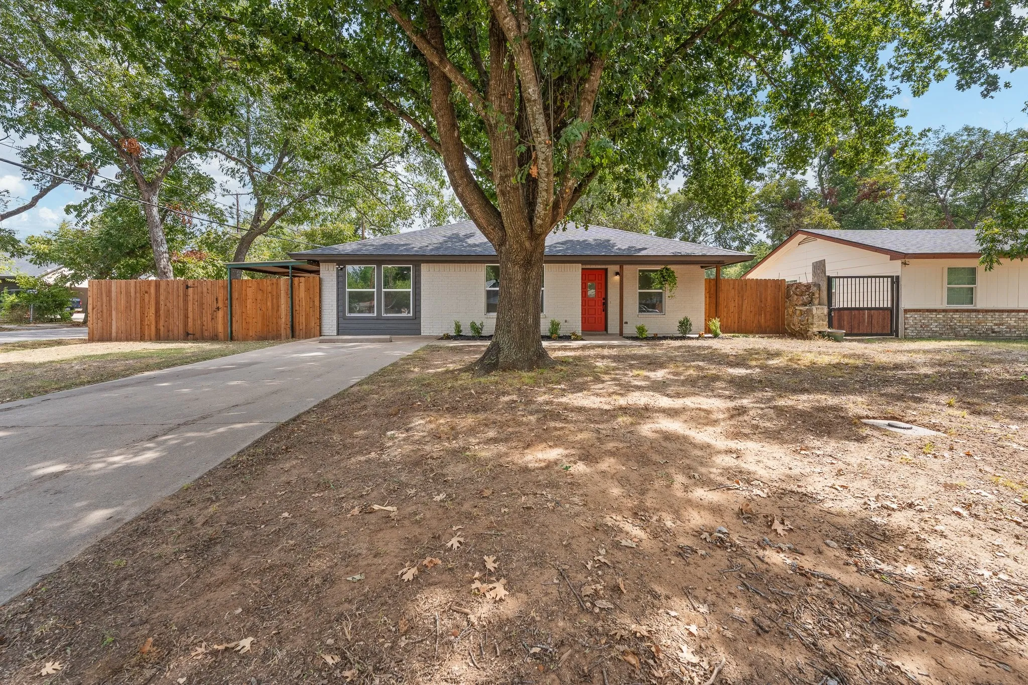 Single-story residence featuring a gray shingle roof, white exterior with gray trim, a red front door, and a concrete driveway