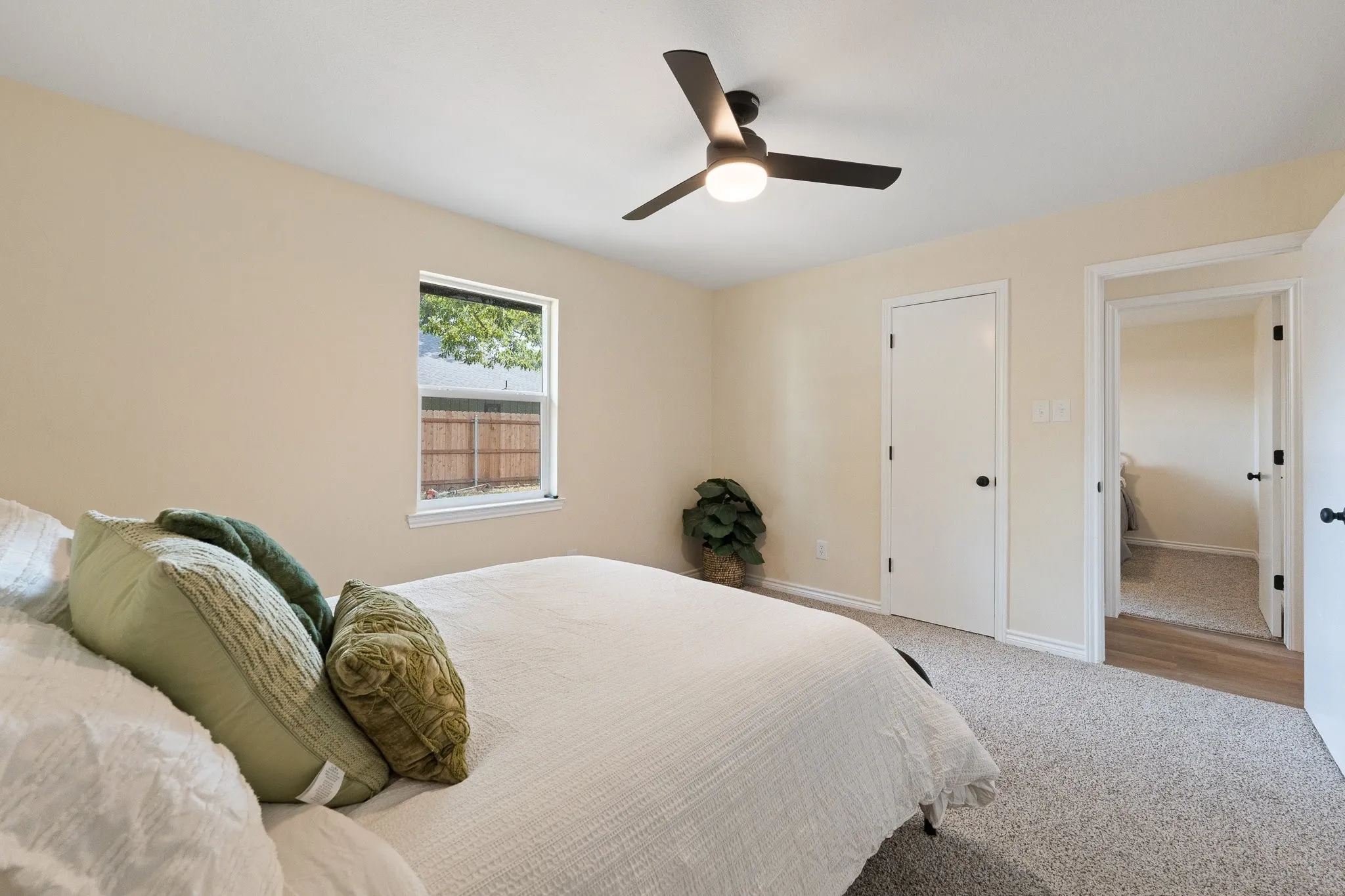 Neutral wall finishes, recessed window, dark ceiling fan with integrated lighting, white interior doors, and light-toned carpeting