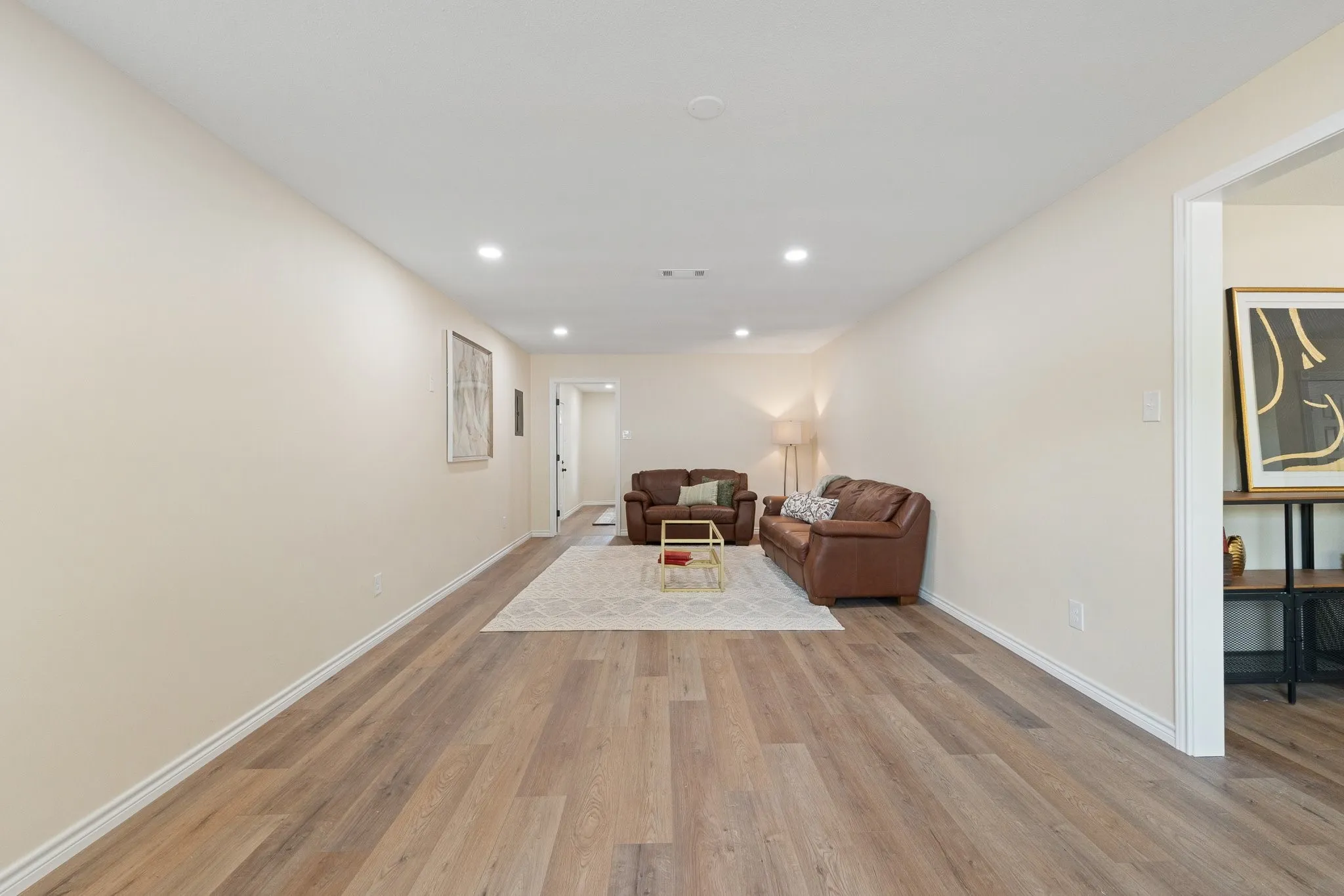 Expansive living area featuring wood-finish flooring, recessed lighting, and a neutral color palette