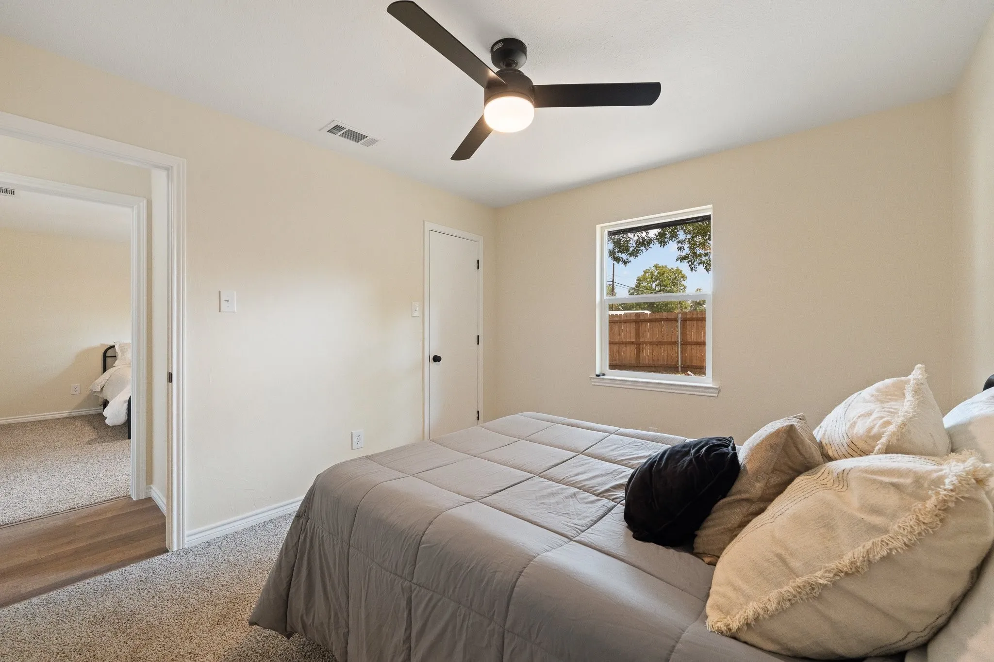 Recessed window with exterior views, ceiling fan with integrated lighting, neutral wall tones, and textured carpeting