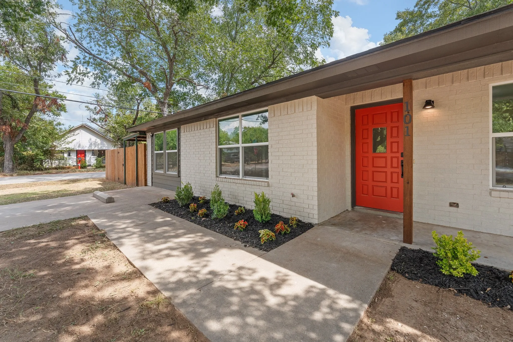 White brick exterior with a vibrant red entry door