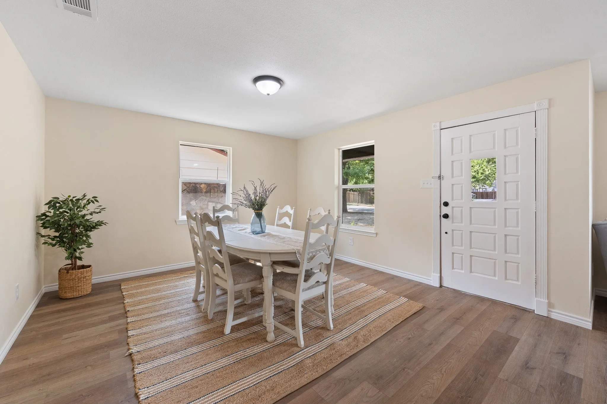 Warm neutral wall tones, durable wood-finish flooring, recessed lighting, and a paneled entry door with window detail