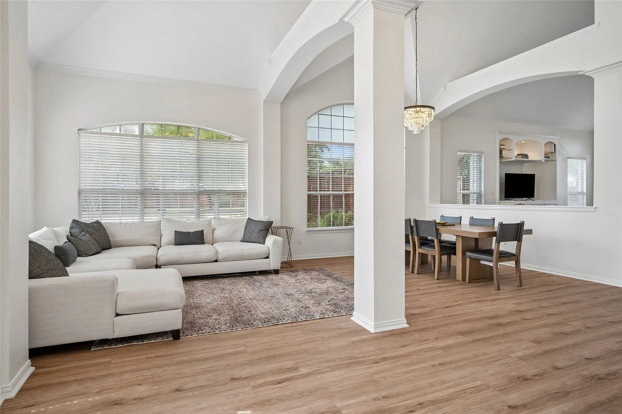 Arched architectural details, wood-finish flooring, high ceilings, and a built-in entertainment center
