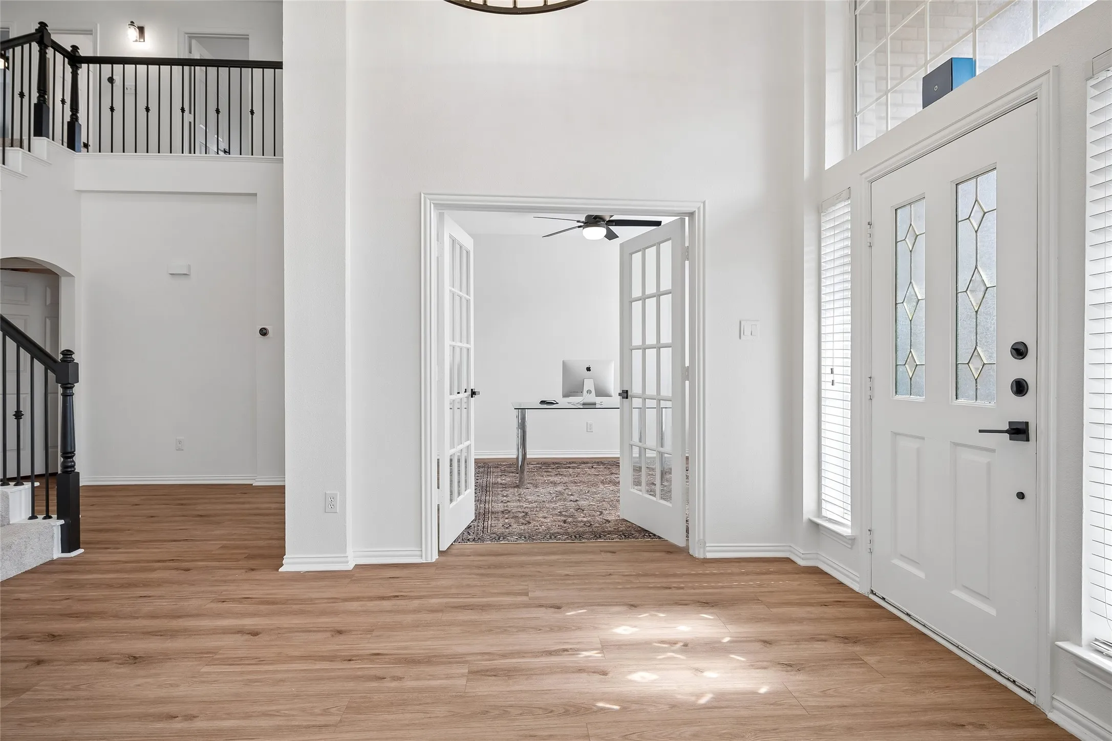 Entryway featuring a decorative glass paneled door, wood-finish flooring, and a two-story foyer