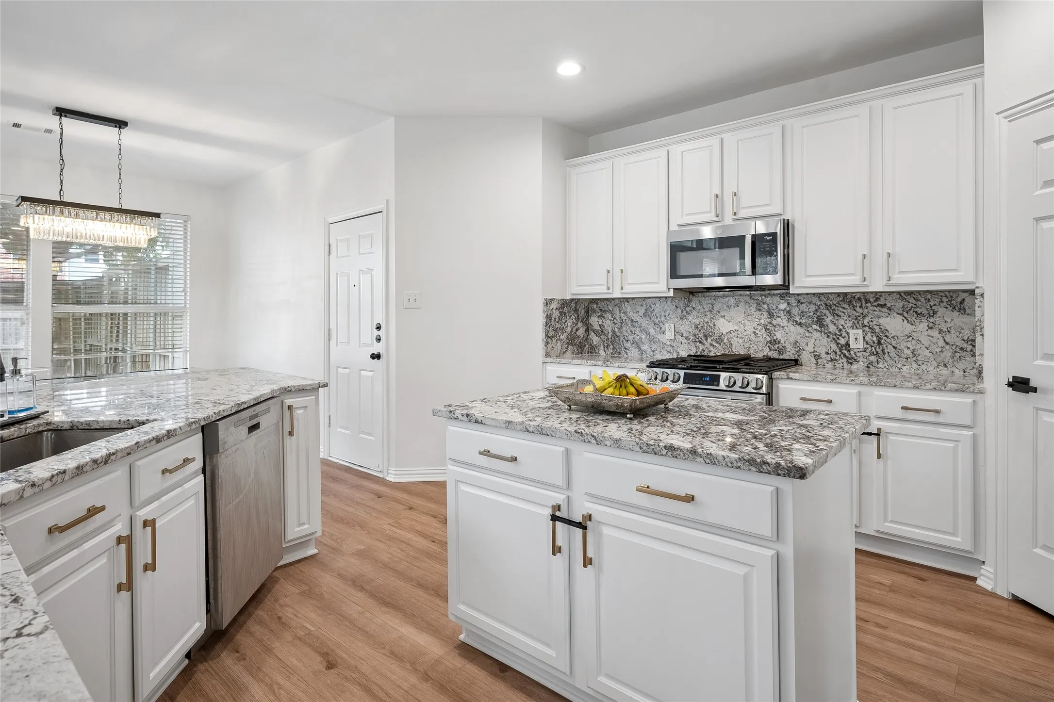 Kitchen featuring white cabinetry, granite countertops, stainless steel appliances, a central island, and wood-finish flooring