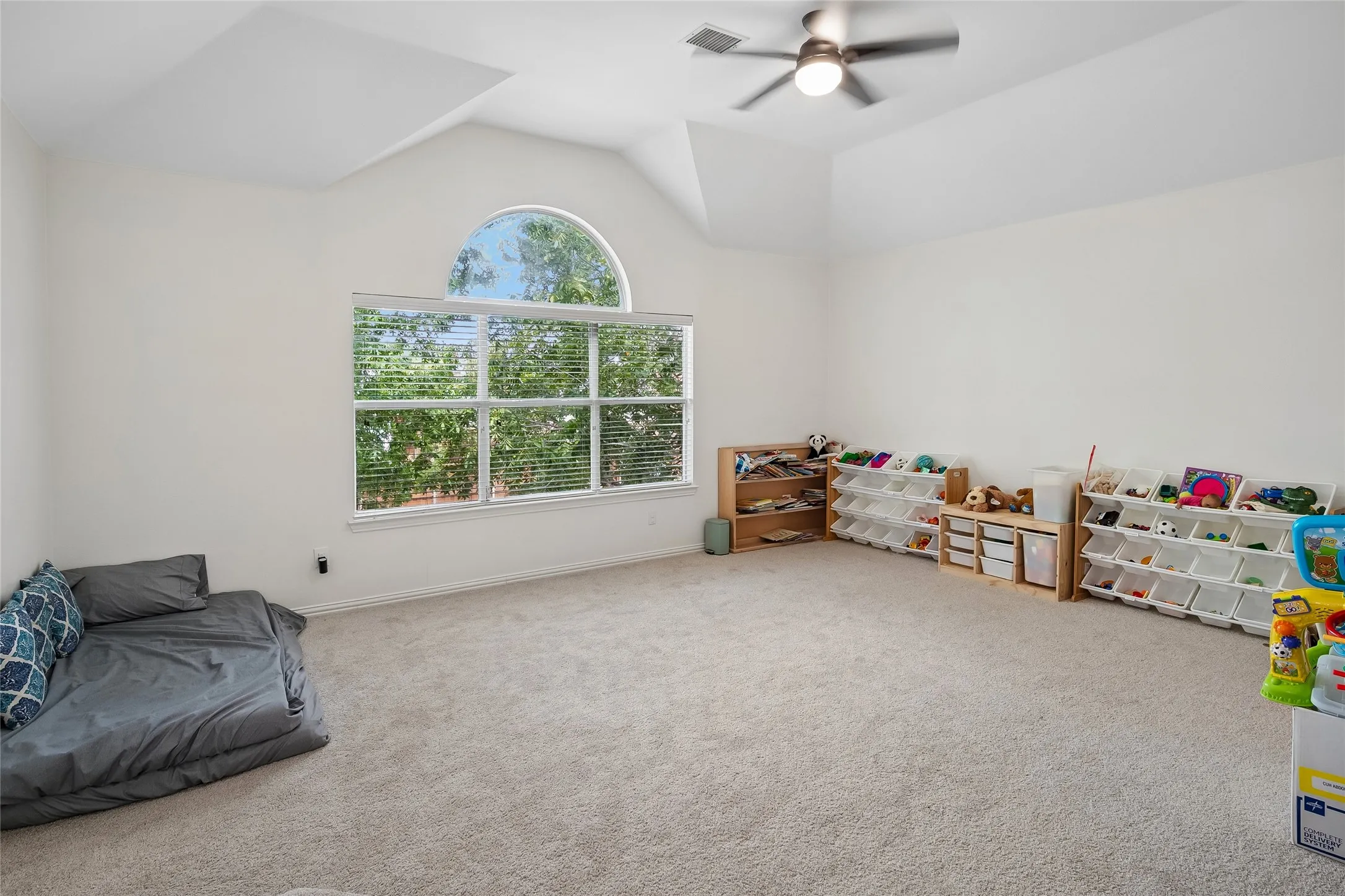 Vaulted ceiling featuring a ceiling fan, large window with blinds, and an arched transom window