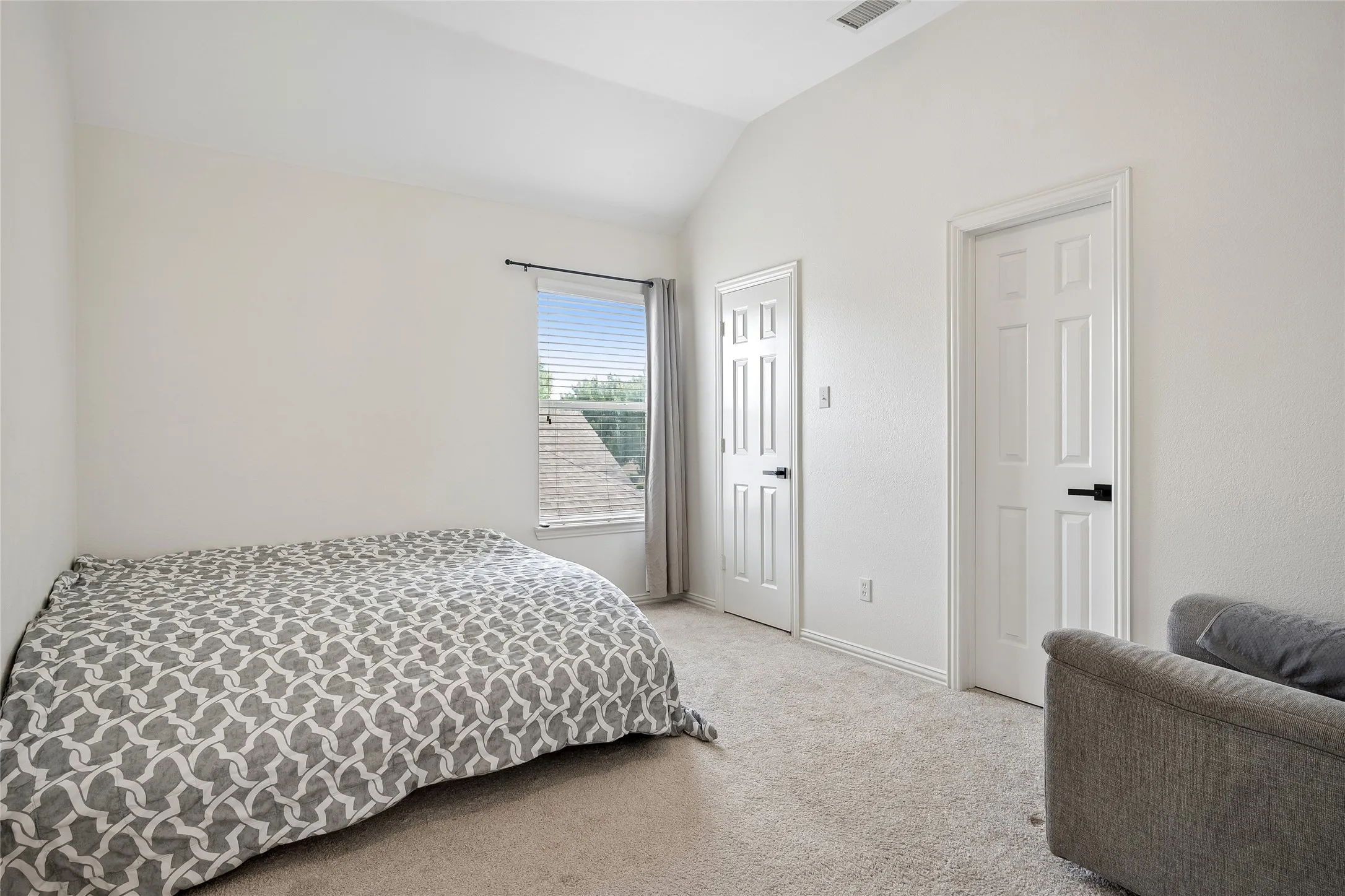 Vaulted ceiling, white walls, two paneled interior doors, and carpet flooring