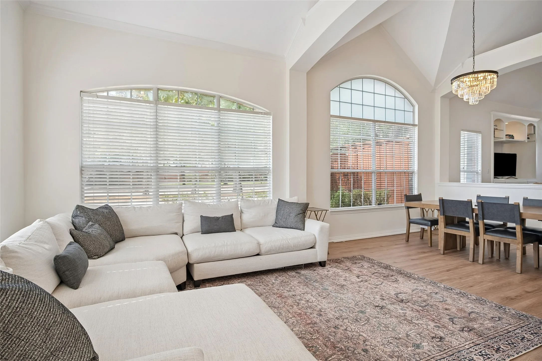 Vaulted ceilings and arched windows illuminate the space, complemented by wood-finish flooring and crown molding