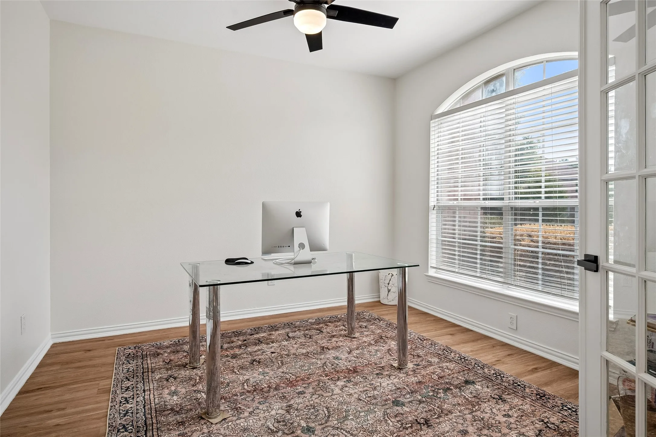 Arched window with blinds, wood-finish flooring, ceiling fan with integrated lighting, and French doors