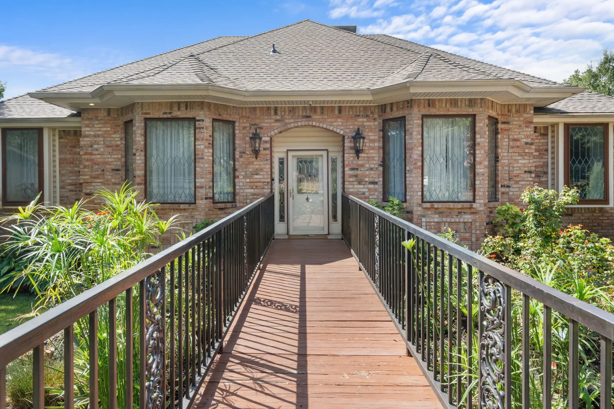 Brick exterior with a gabled roofline, decorative bay windows, and a wide wooden ramp entry with metal railings
