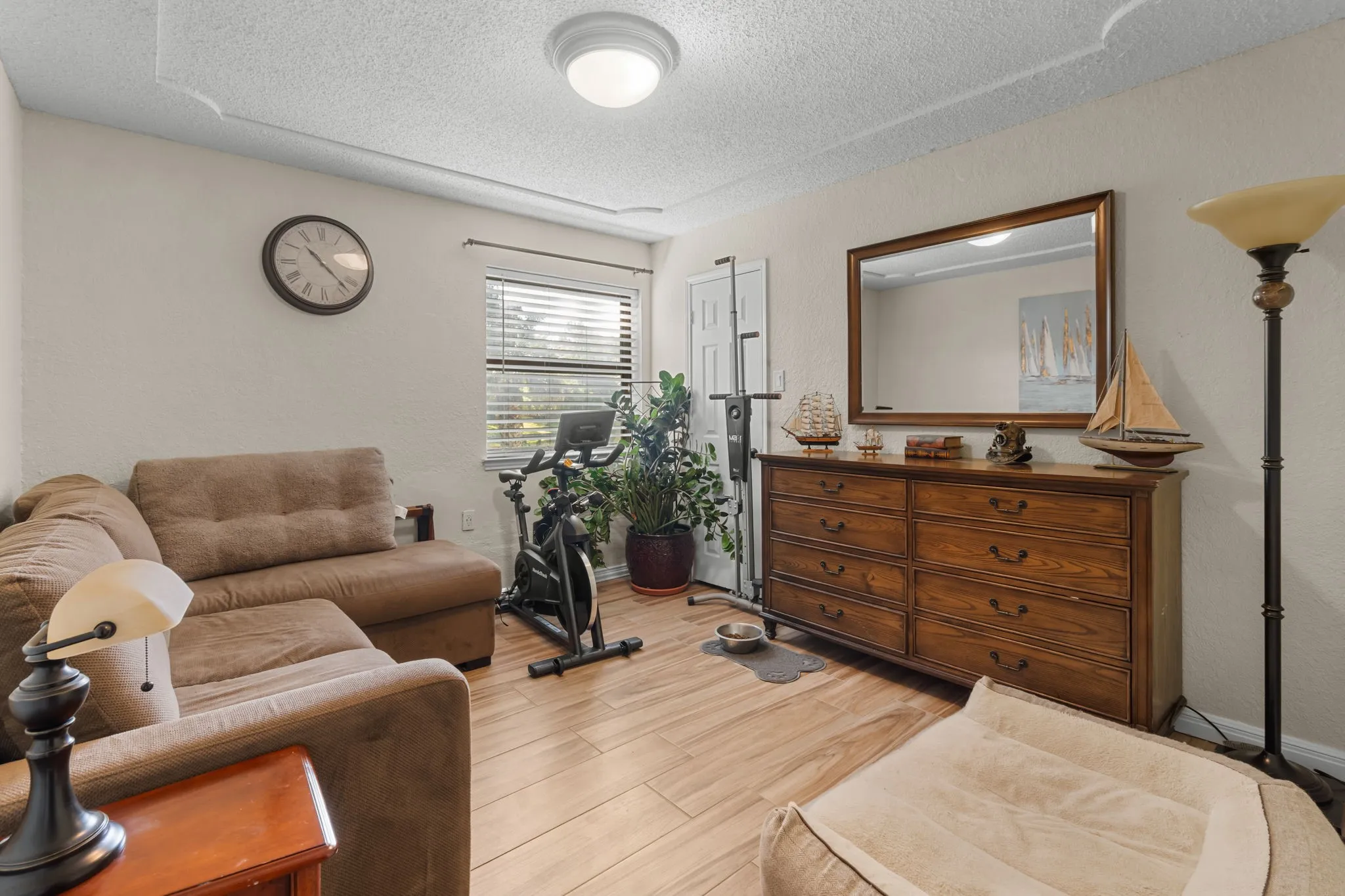 Wood-finish flooring throughout, with a window featuring horizontal blinds