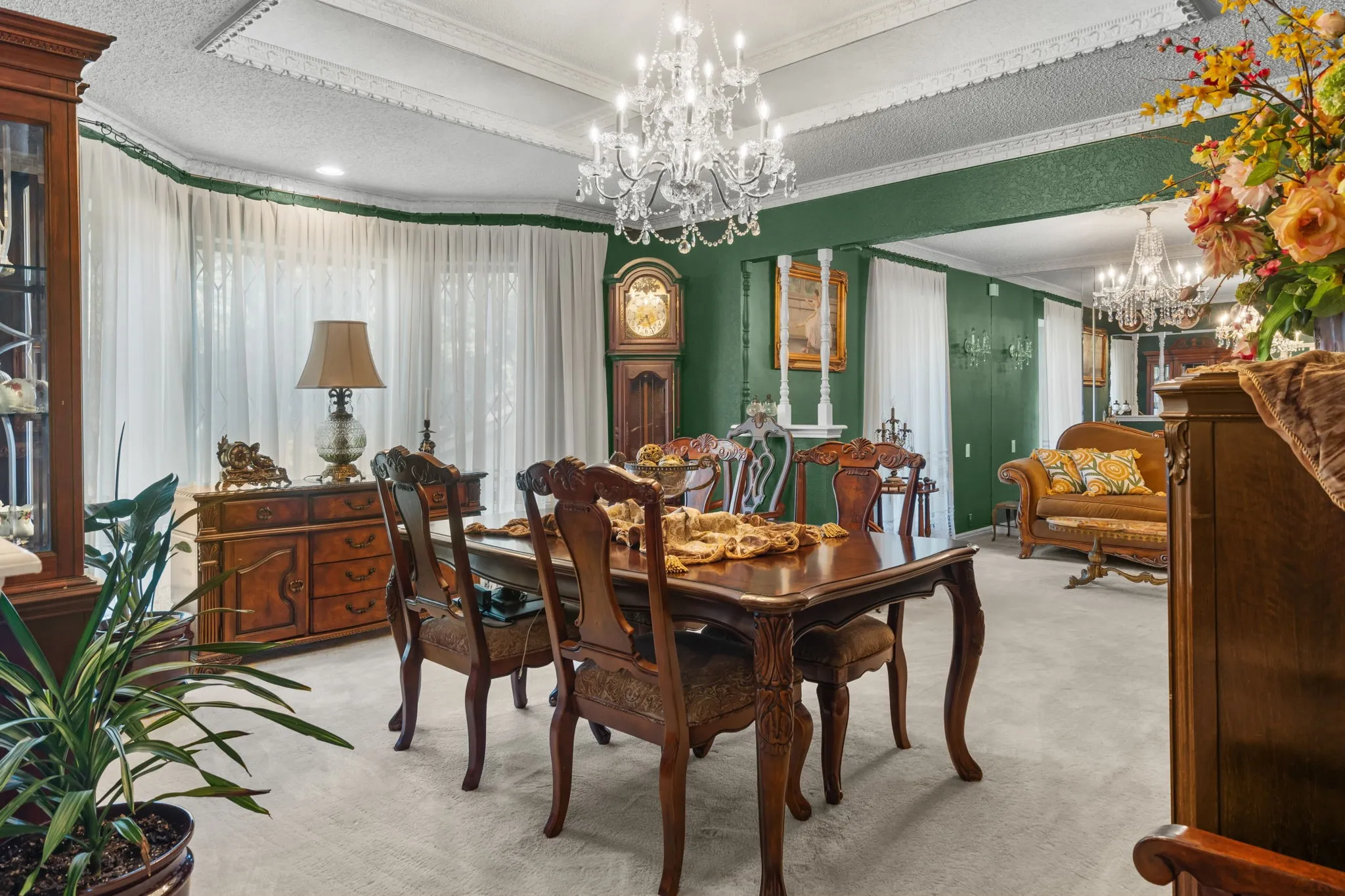 Spacious dining area featuring a prominent chandelier, tray ceiling with decorative molding, and bay windows