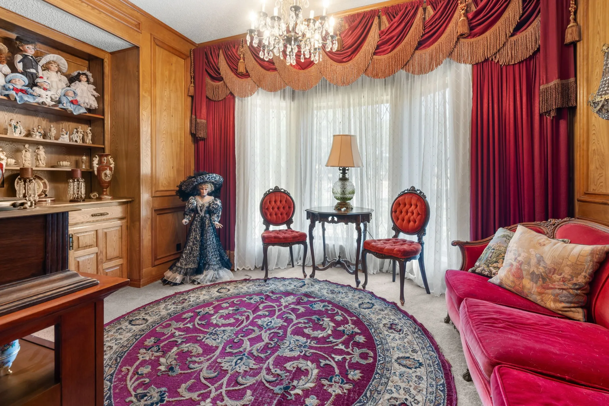 Wood paneling with built-in shelving, ornate chandelier, and full-length window treatments