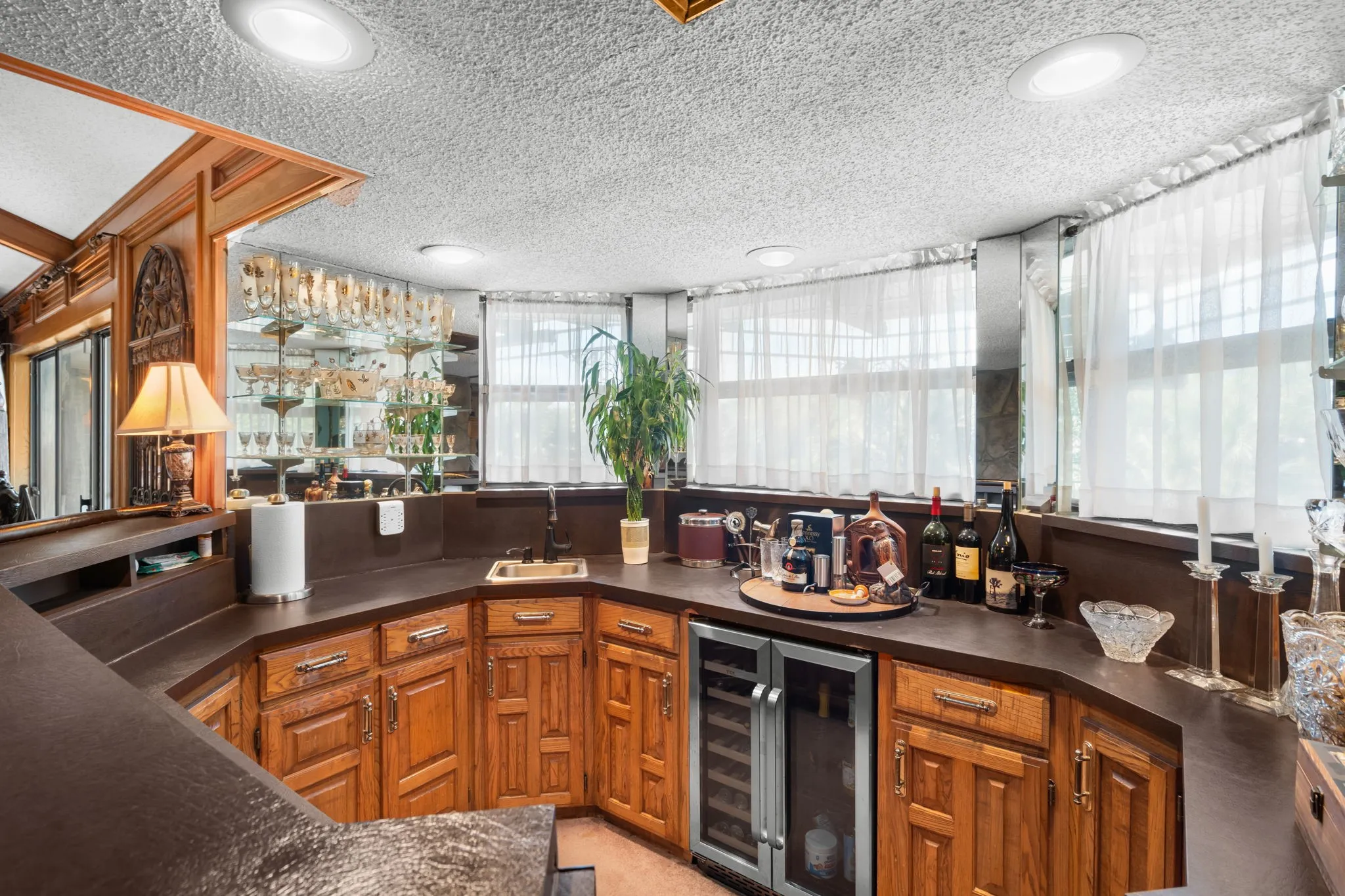 Built-in wet bar featuring a sink, integrated beverage cooler, wood cabinetry, and recessed lighting