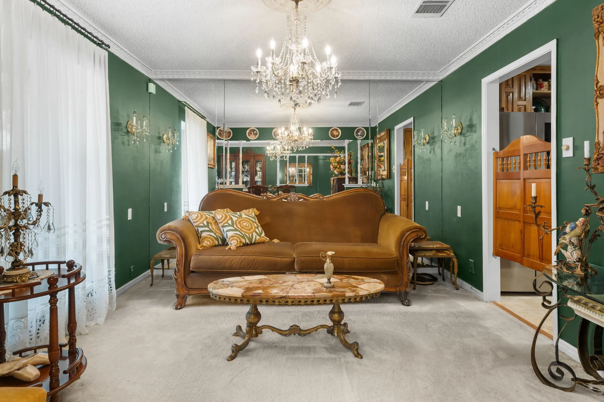Living area with green wall paneling, wall-mounted sconces, and a detailed chandelier