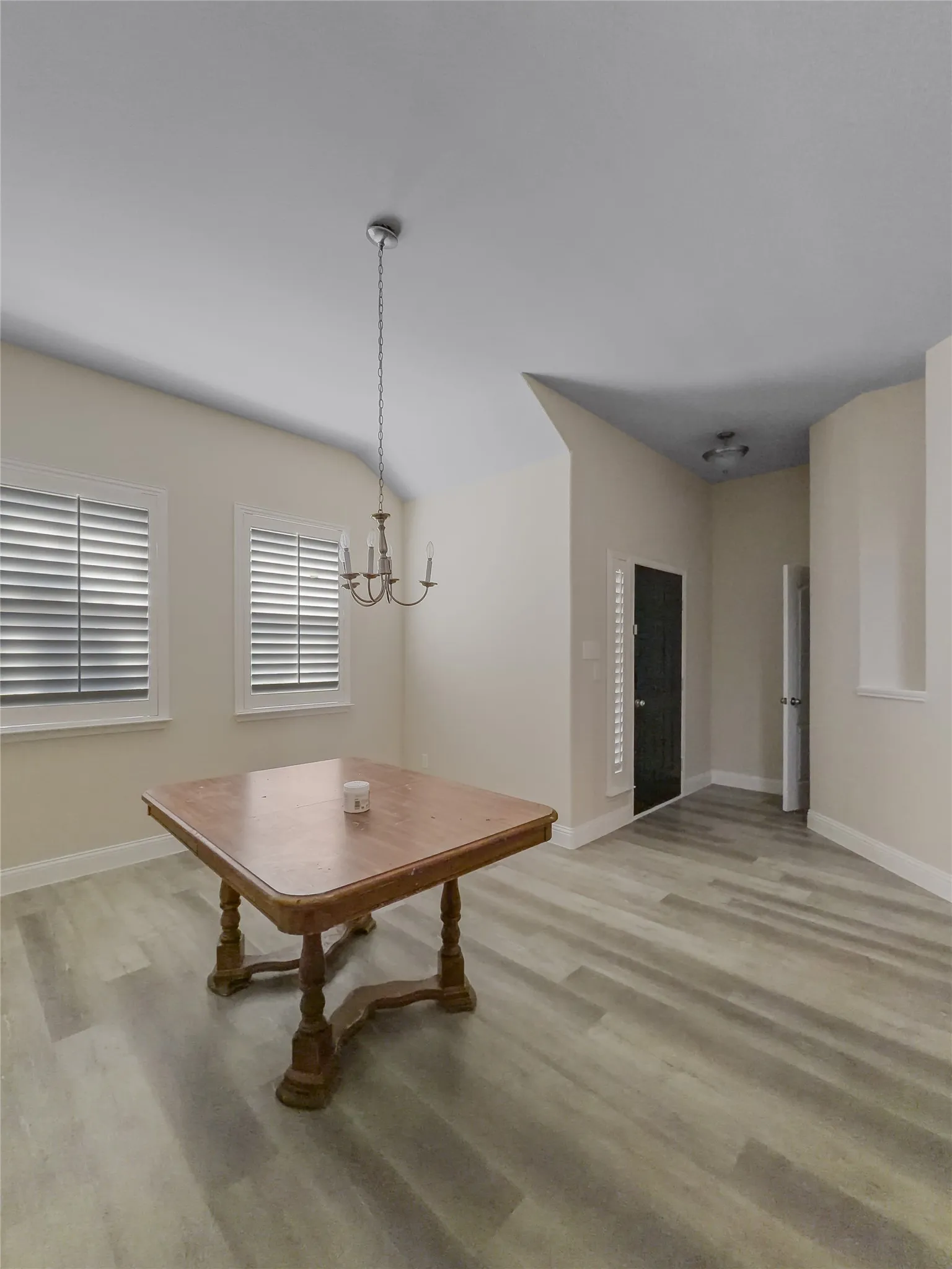 Light gray wood-finish flooring, two windows with plantation shutters, recessed lighting, and a pendant light fixture