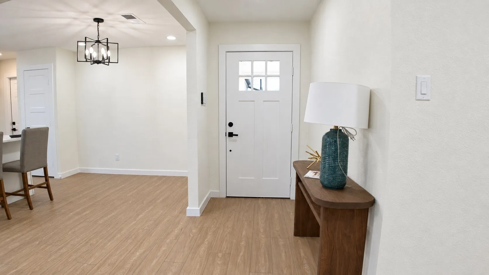Entryway featuring a white paneled door with glass inserts, wood-finish flooring, and a contemporary black chandelier