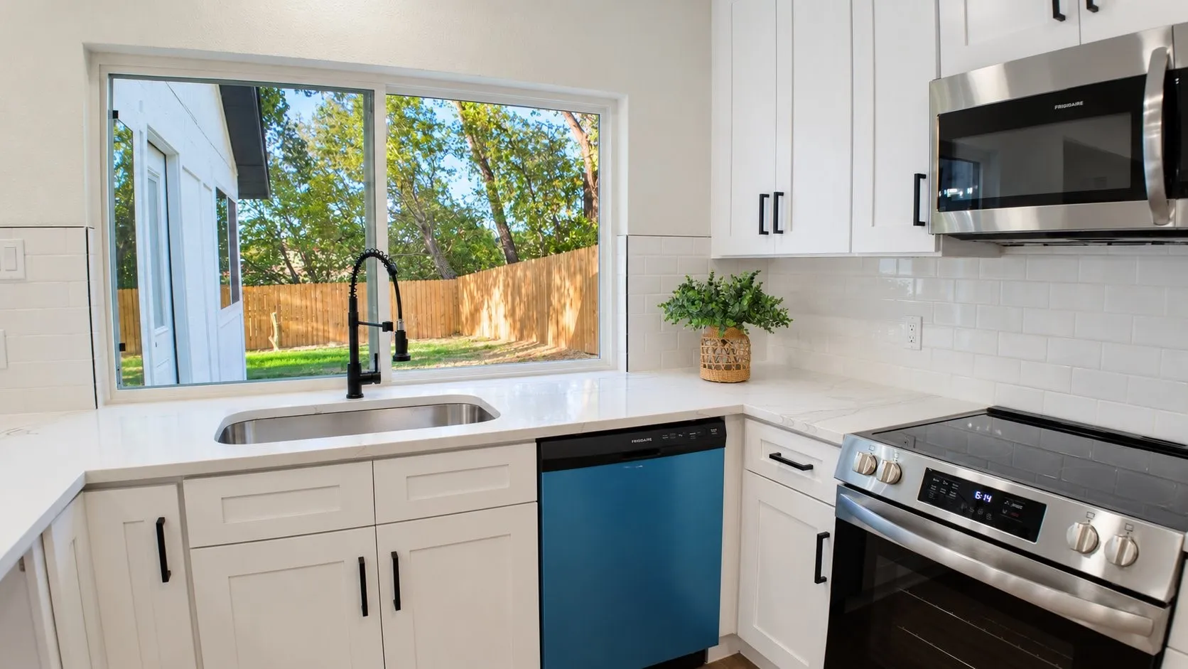White shaker cabinetry with matte black hardware, stainless steel appliances, white subway tile backsplash, white countertops, and a stainless steel sink with a black faucet