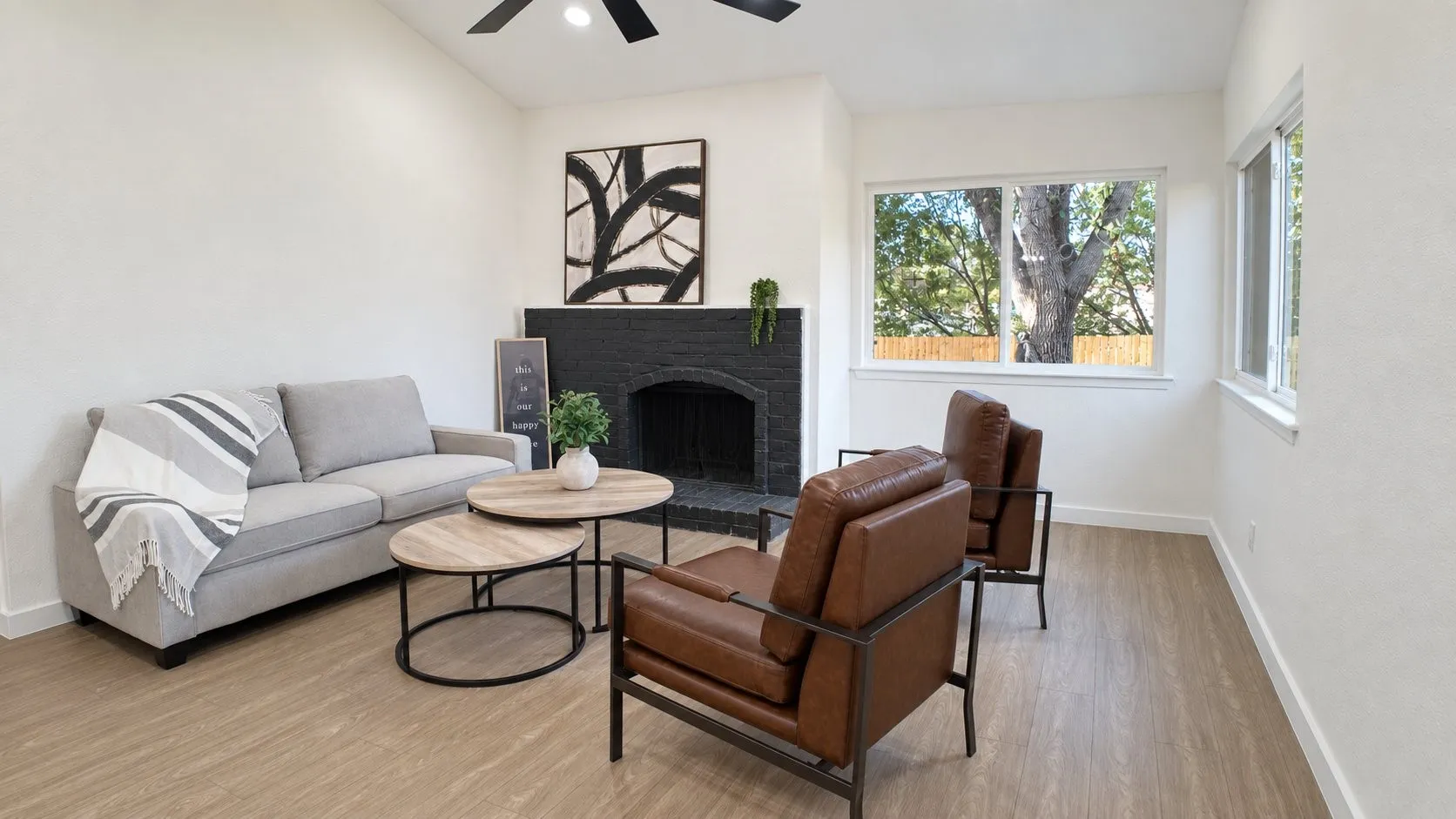Spacious living area featuring light wood-finish flooring, white walls, and multiple windows