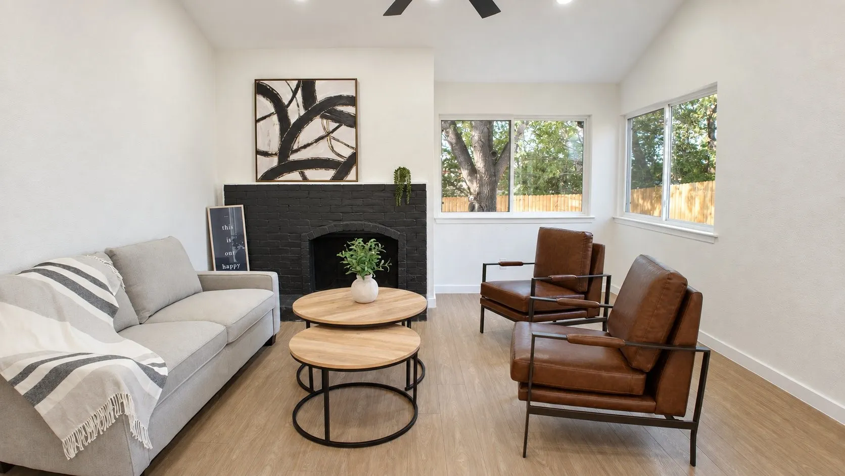 Light wood-finish flooring, white walls, and a black brick fireplace